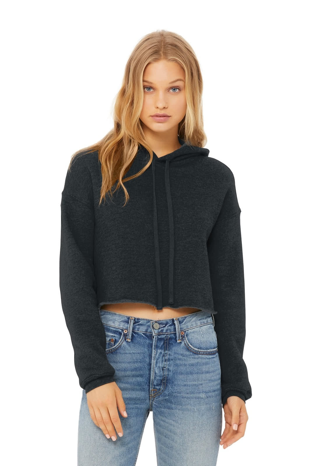 A cropped fleece hoodie in dark grey, featuring a front pocket and a drawstring hood. The model pairs it with blue jeans.