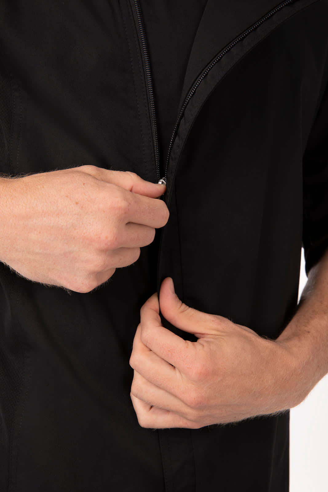 A black chef jacket featuring a front zipper, with hands adjusting the zip. Includes a branding logo.