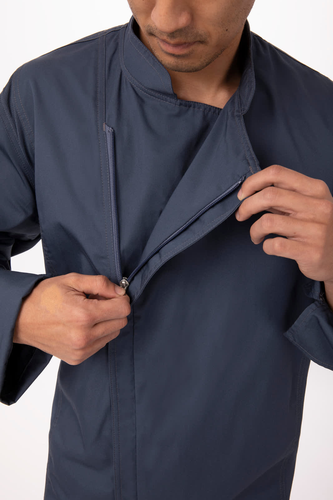 A navy chef jacket is being buttoned up by a person, featuring a collar and long sleeves. It has a logo on the fabric.