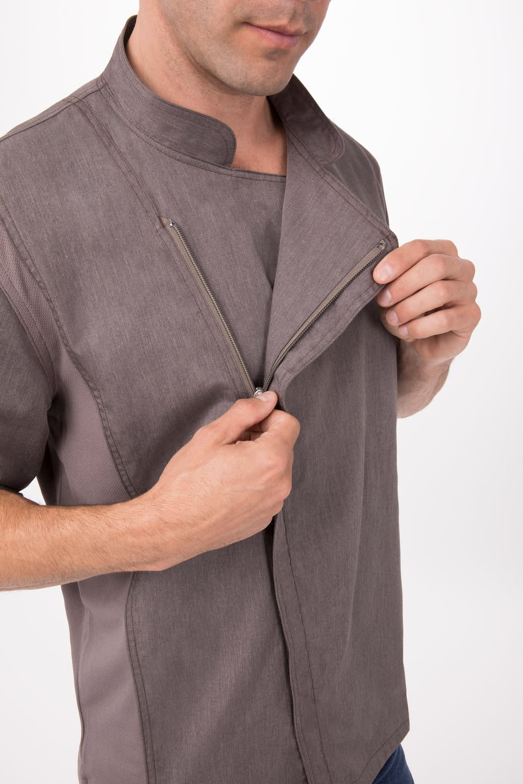A grey chef jacket with a zippered front, worn by a person with their hand on the zipper.
