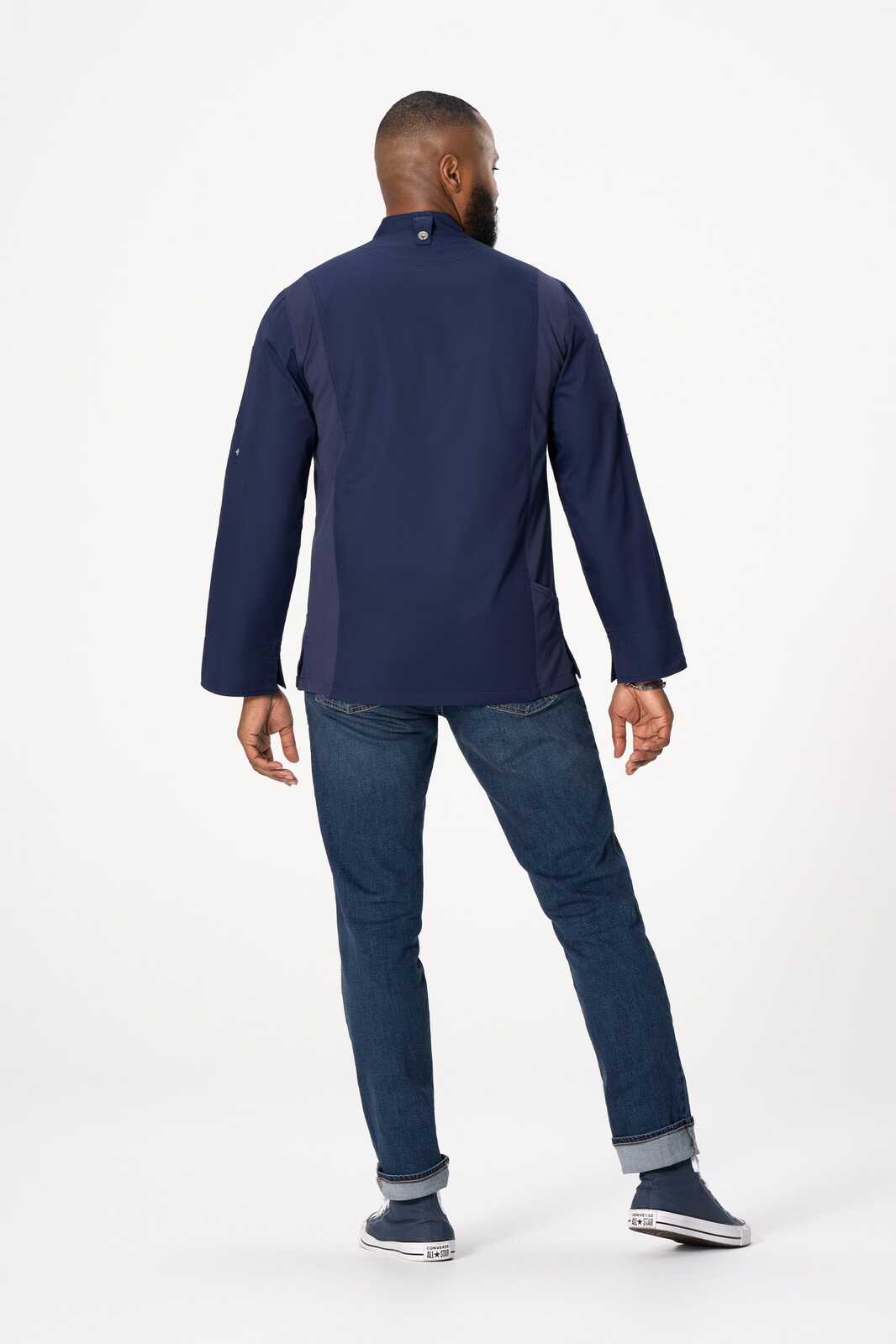 A men's chef jacket in navy blue, featuring long sleeves and a collar, worn with denim jeans and casual shoes.