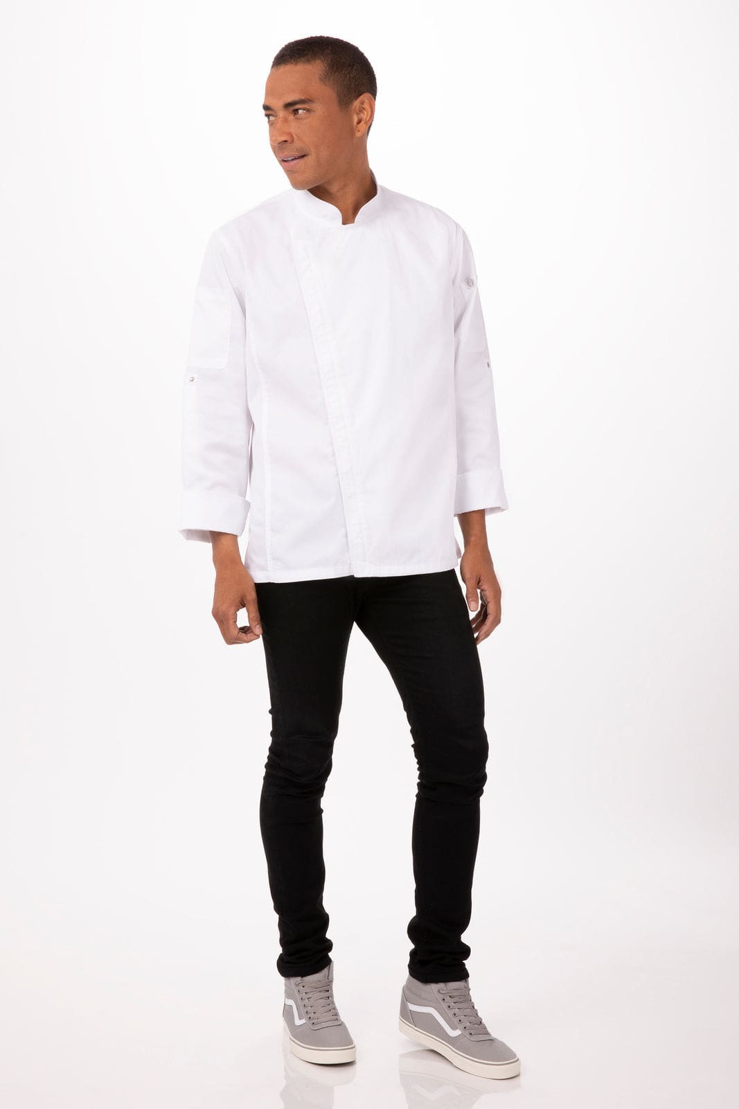 A man wears a white chef jacket paired with black pants and grey shoes, standing against a plain background.