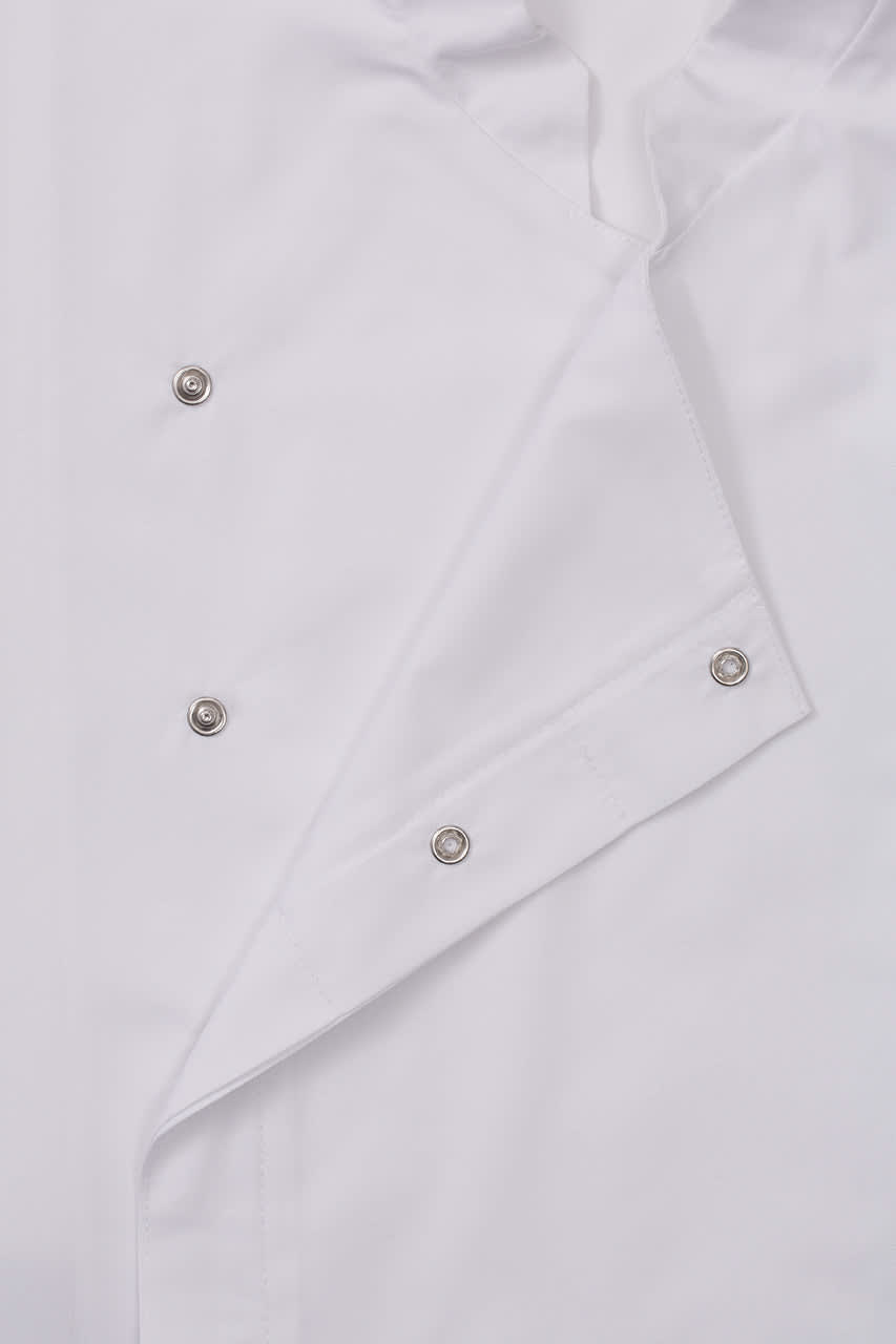 A white chef jacket with silver snap buttons, featuring a classic design and a logo on the chest area.