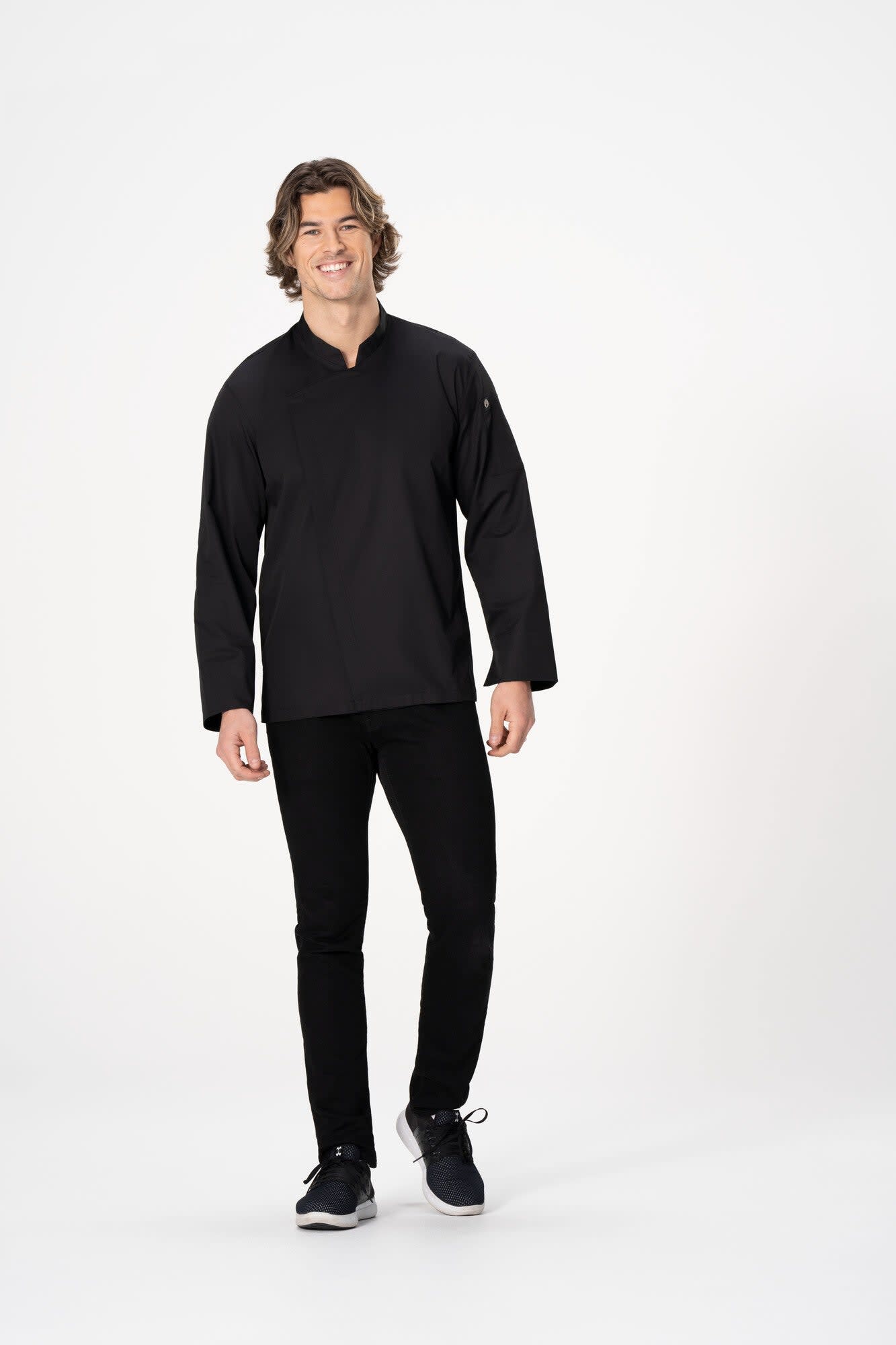 Men's chef jacket in black, featuring long sleeves and a mandarin collar. Model wearing it with dark trousers and shoes.