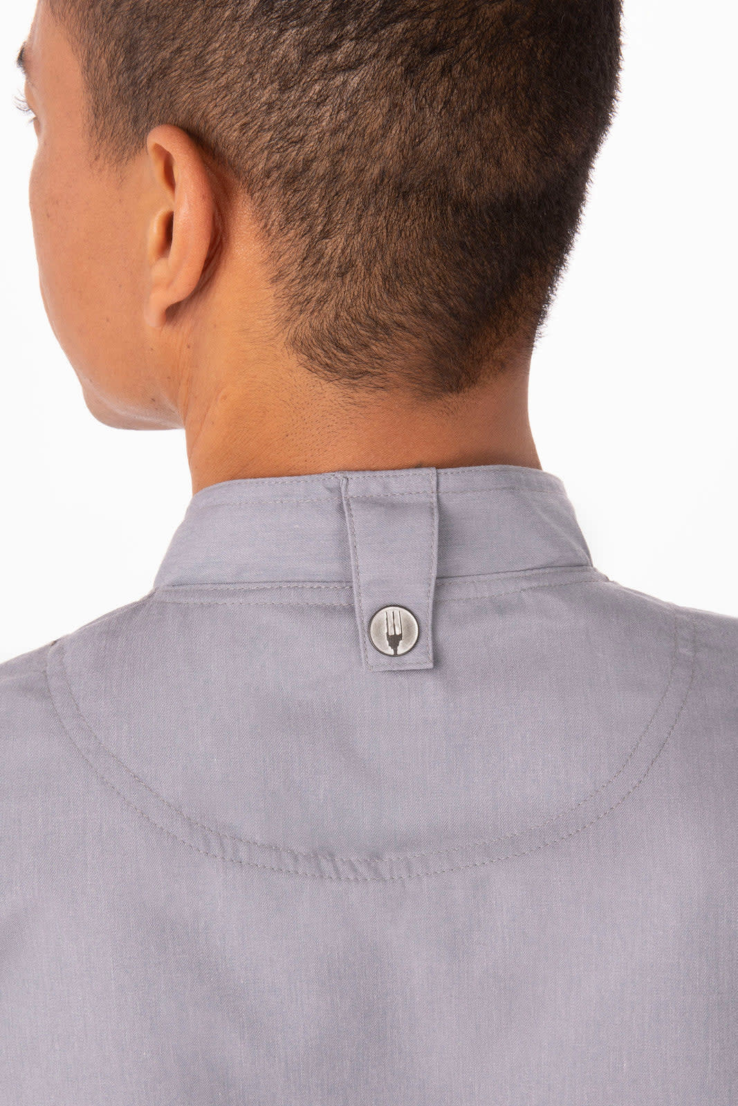 A grey chef jacket with a collar featuring a button detail at the back. It has a logo on the fabric.