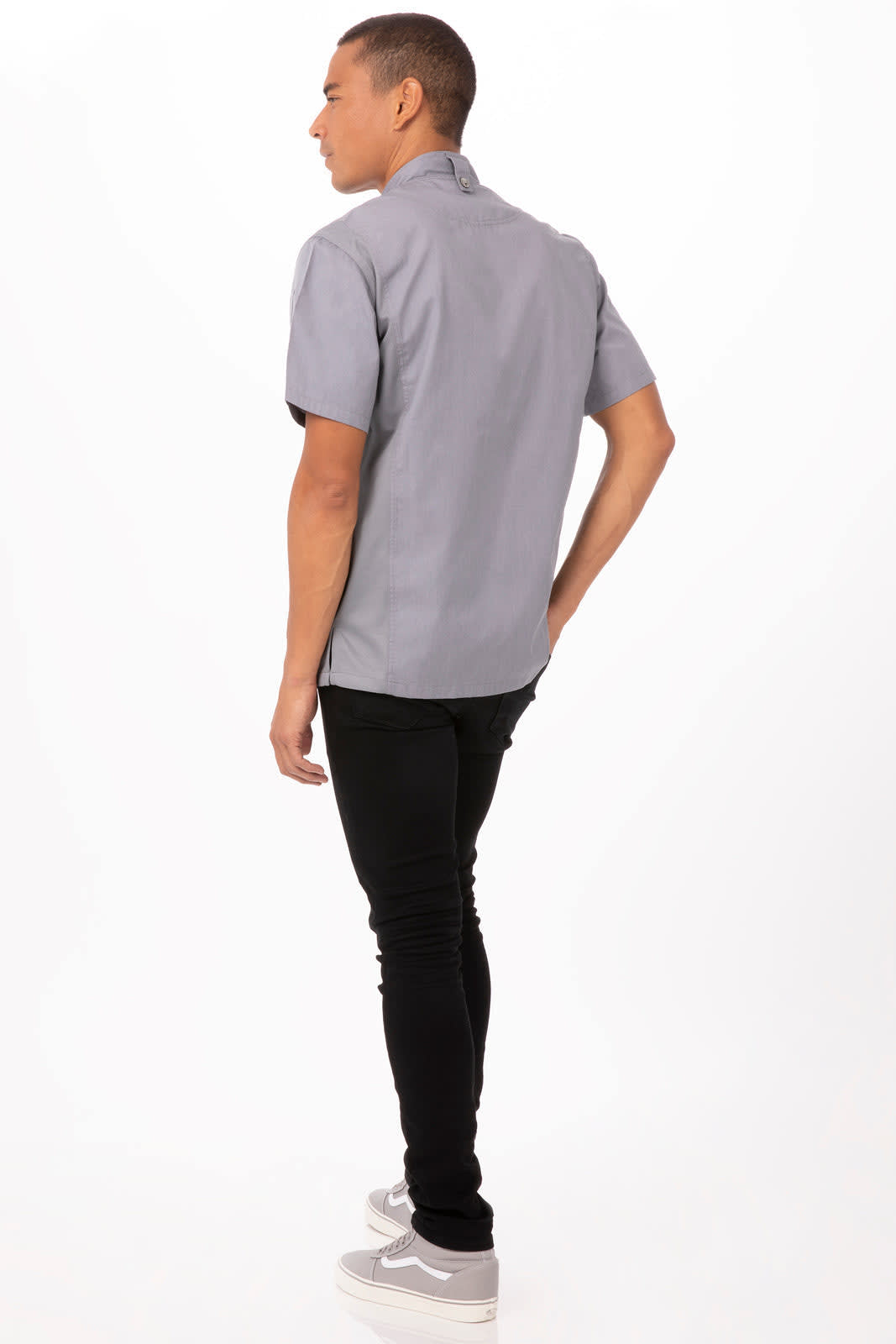 A grey short-sleeved chef jacket is worn by a man facing away, paired with dark pants and shoes.