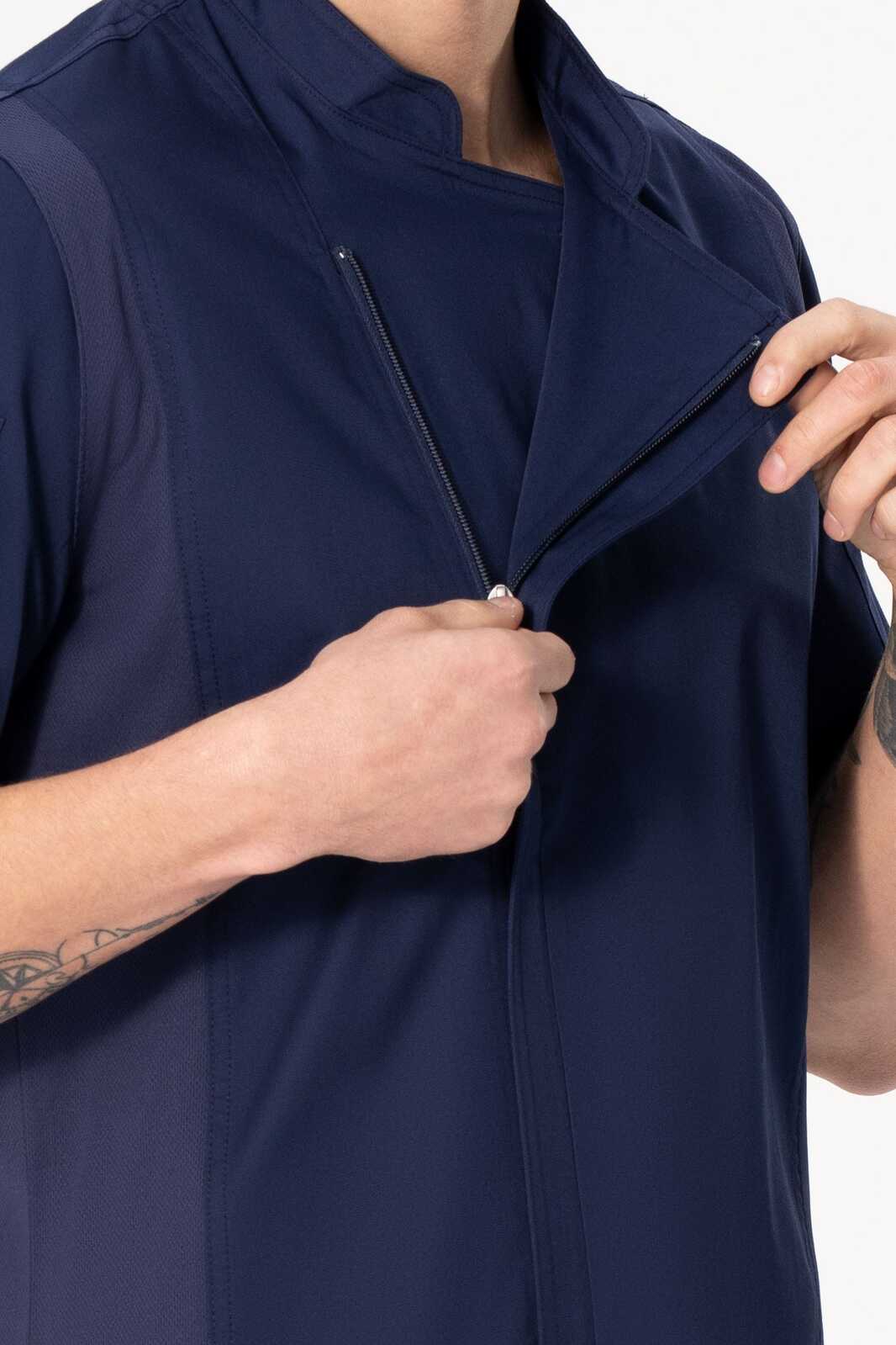 A navy blue chef jacket featuring a zippered front and a stand-up collar. The model is adjusting the jacket.