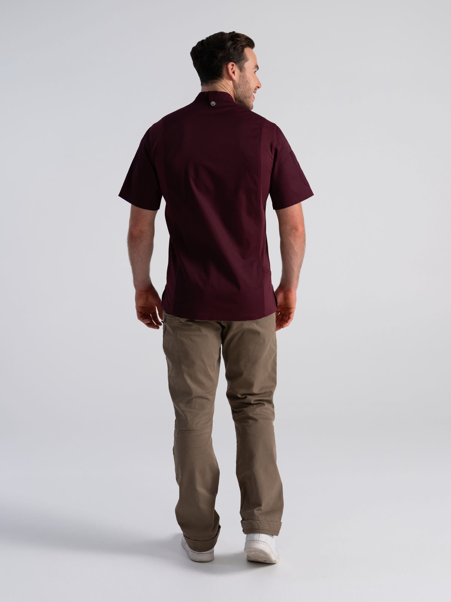 A man's chef jacket in burgundy, featuring short sleeves, paired with beige pants, and showing a branded logo.