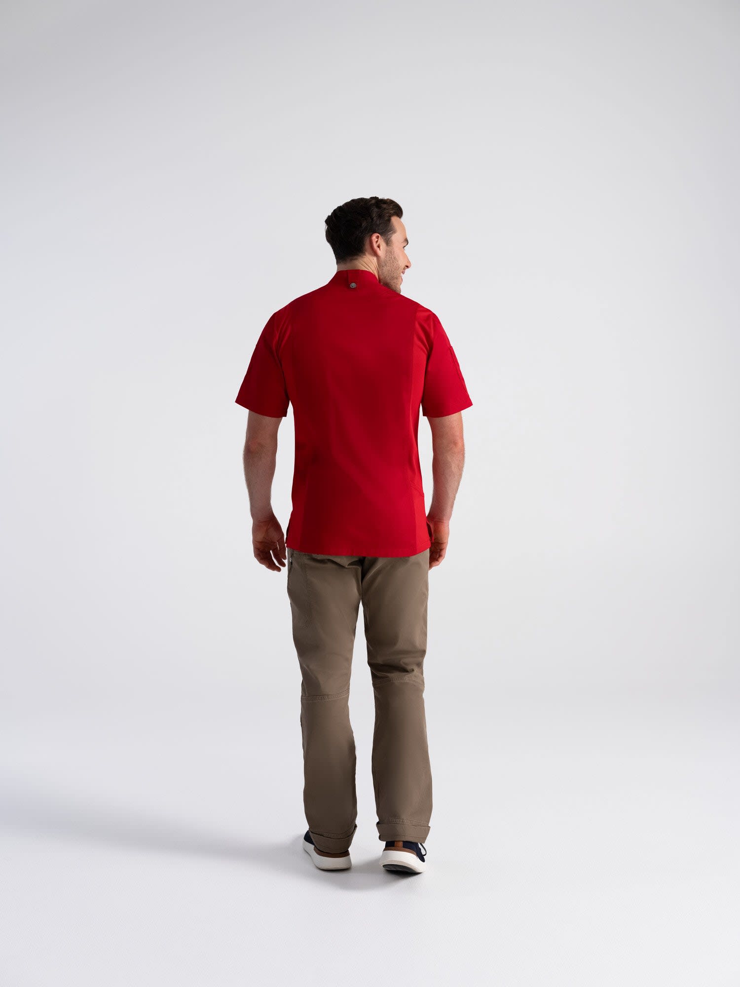 A red chef jacket displayed from the back, worn with beige pants, featuring a logo on the collar.