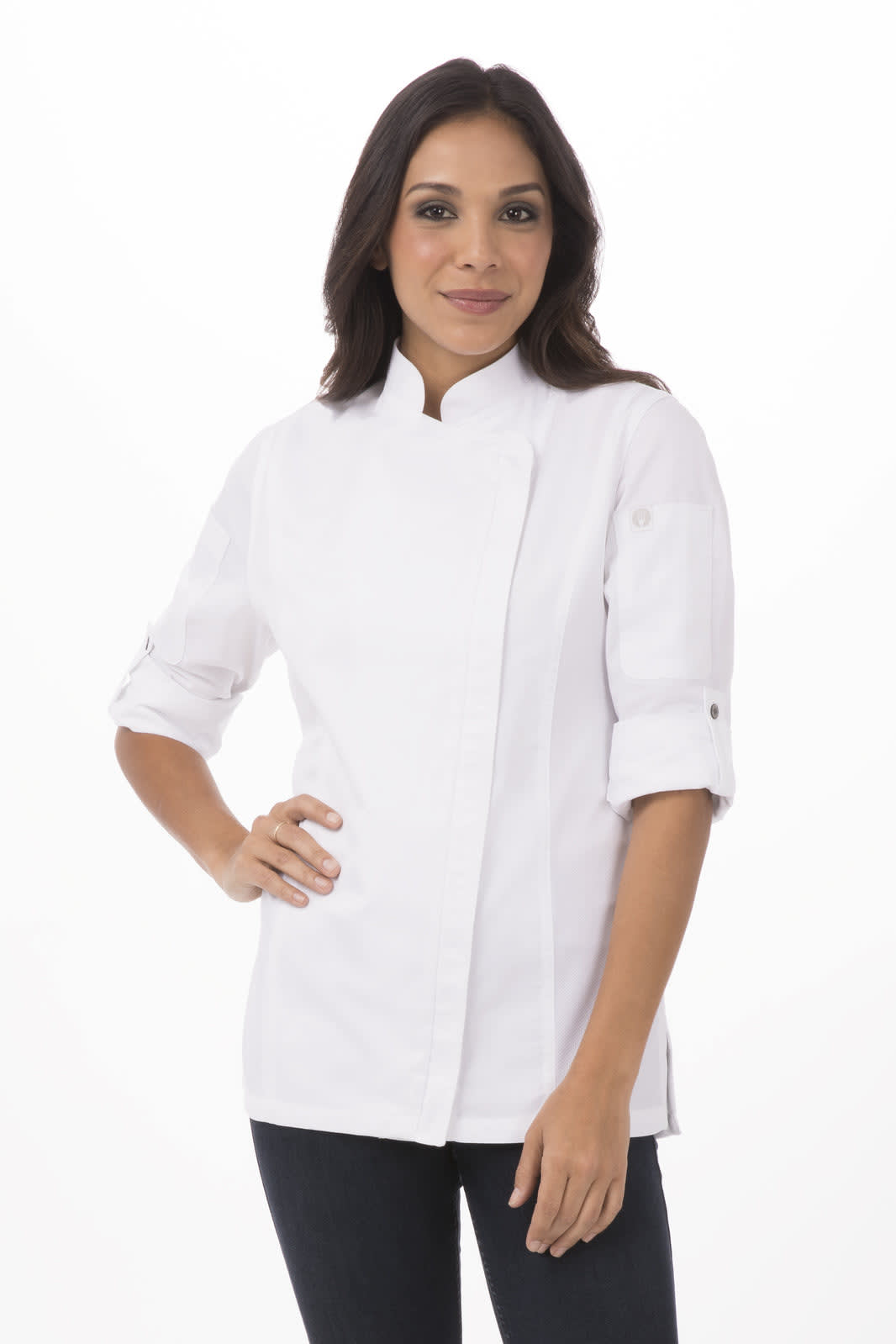 A woman in a white chef jacket is posing, wearing black pants with rolled-up sleeves. The jacket features a logo.