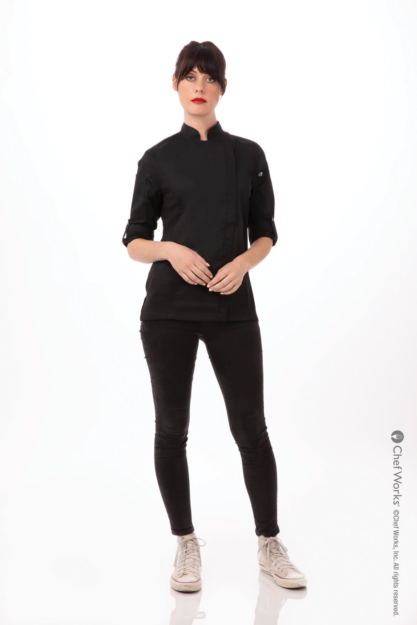 A black women's chef jacket featuring a stand collar and rolled sleeves, worn by a model with dark hair.