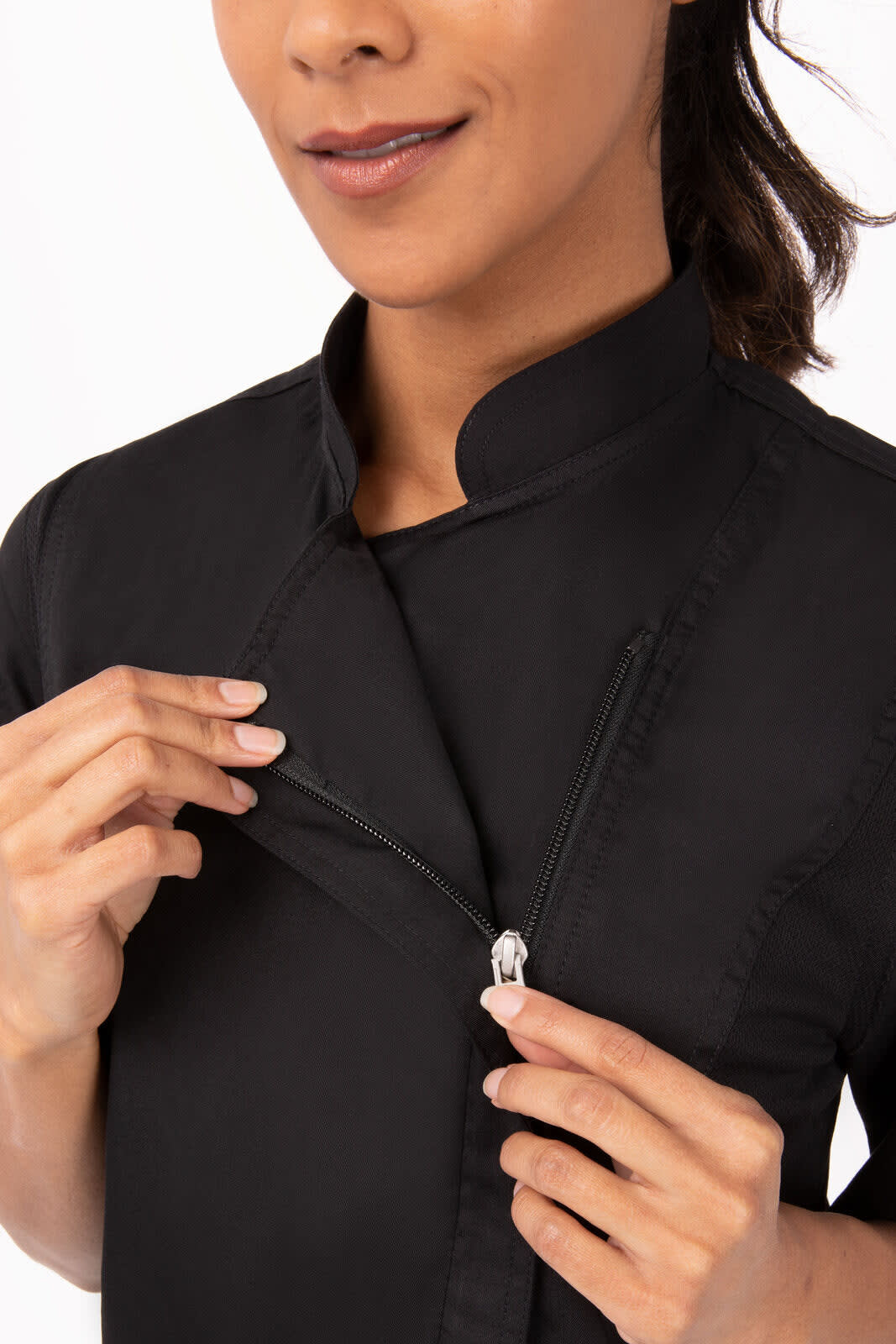 A close-up of a woman in a black chef jacket, featuring a zippered front and a high collar. The jacket has a logo.