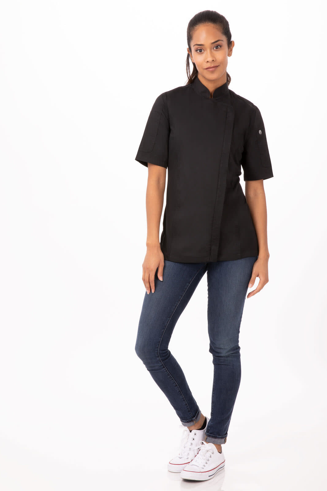 A black women's chef jacket worn by a model, paired with denim jeans and white sneakers, featuring a logo on the sleeve.