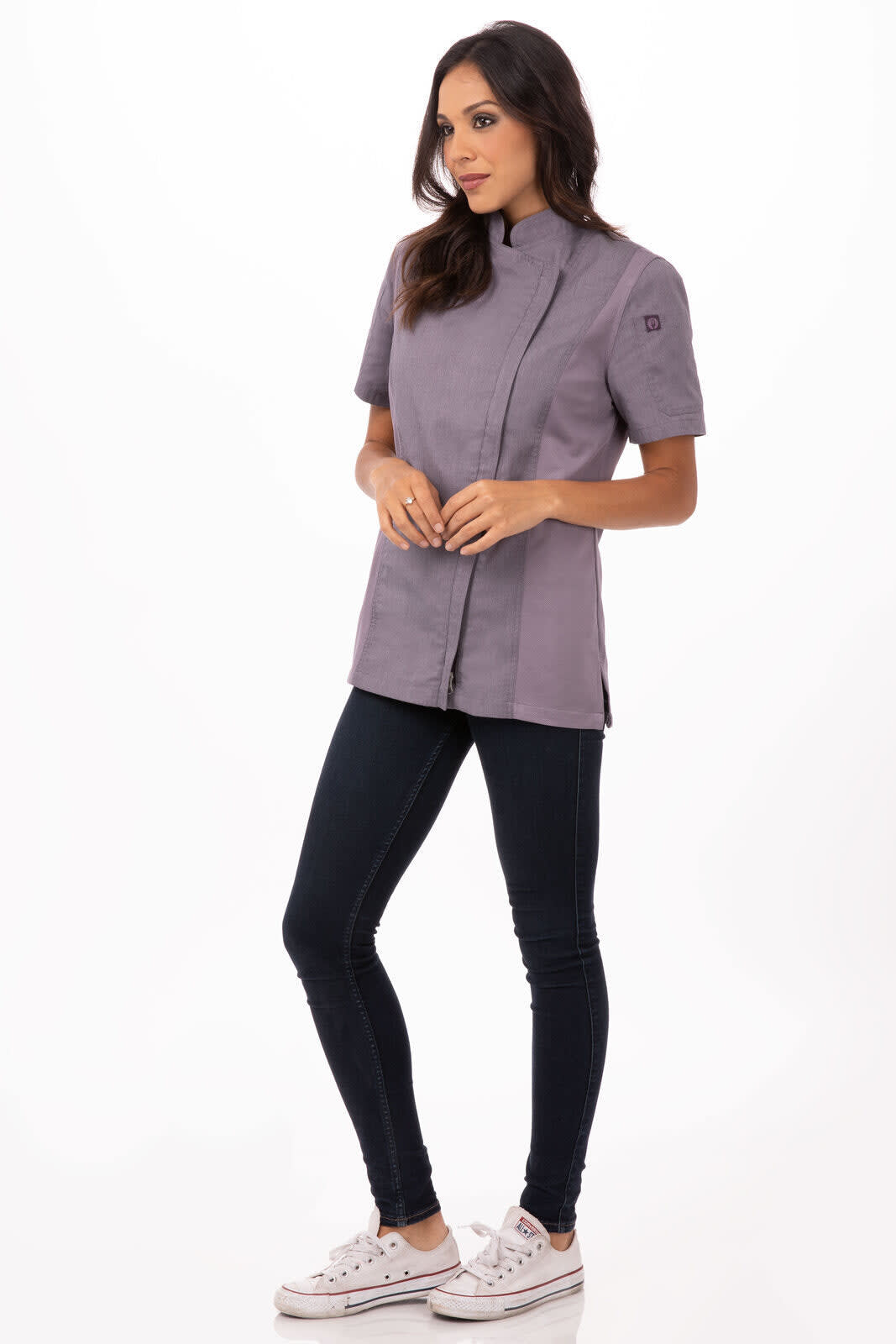 A chef jacket in a soft grey colour is worn by a model, paired with dark jeans and white sneakers. It features a branding logo.