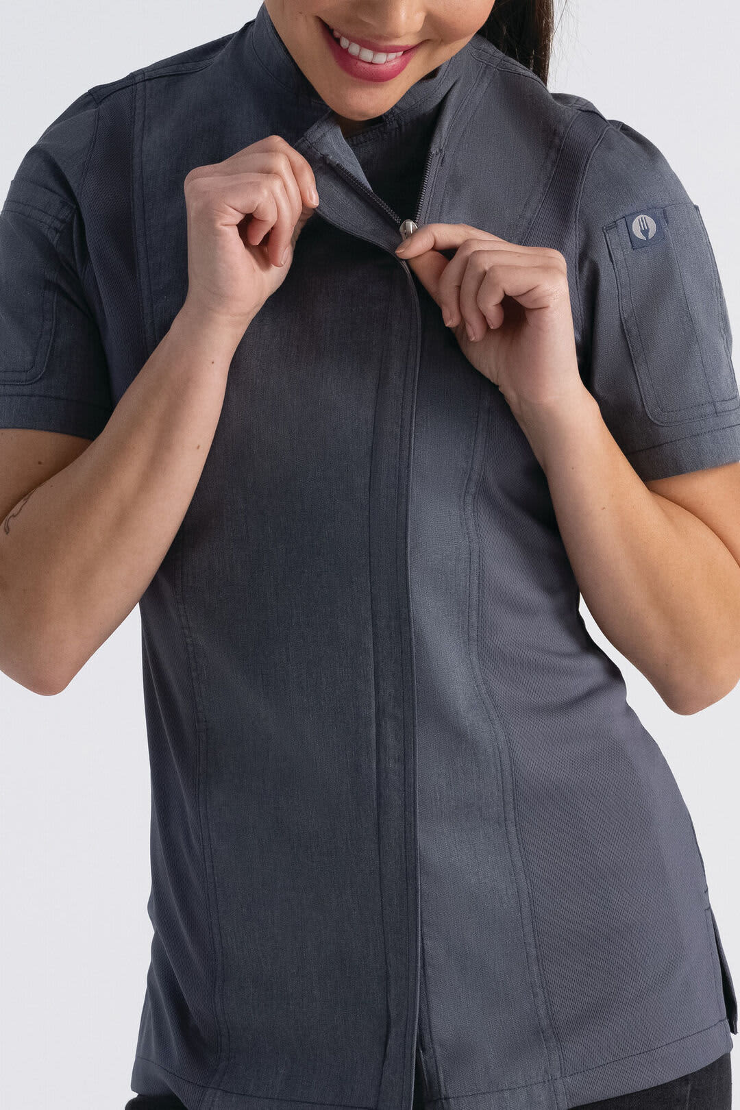 A grey women's chef jacket featuring a high collar and short sleeves, with a logo on the sleeve.