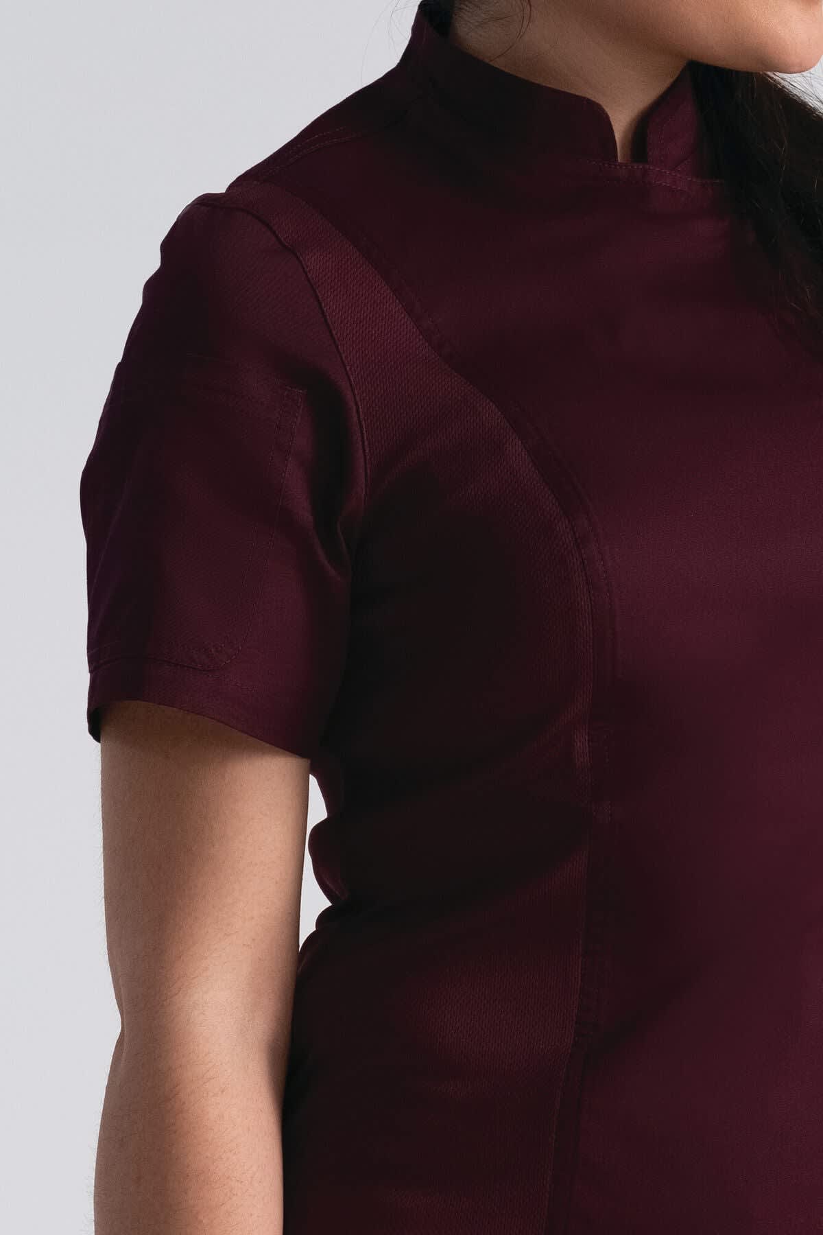 A burgundy chef jacket with a fitted design and short sleeves, featuring a stand-up collar and a logo.