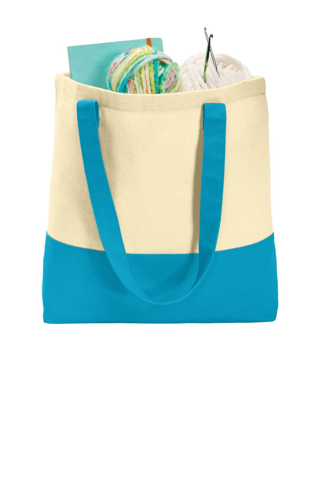 A tote bag with a cream upper section and turquoise bottom, filled with yarn and crafting supplies.