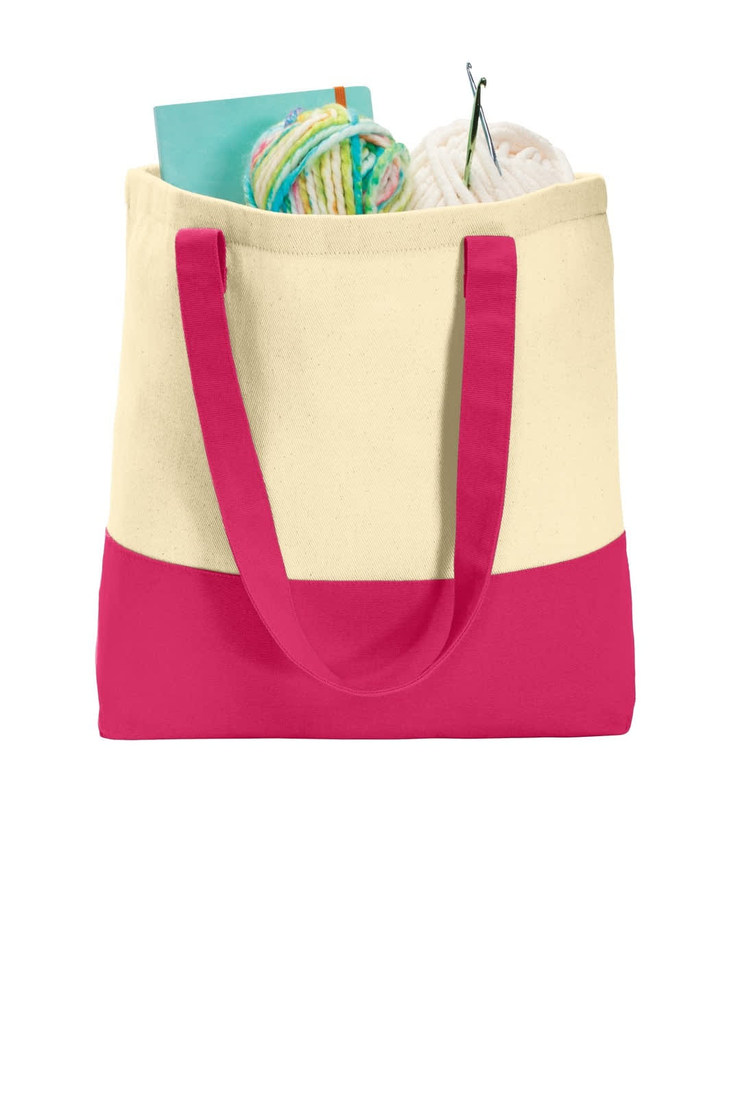 A cream tote bag with a pink bottom, filled with yarn, knitting needles, and a stack of colourful papers.