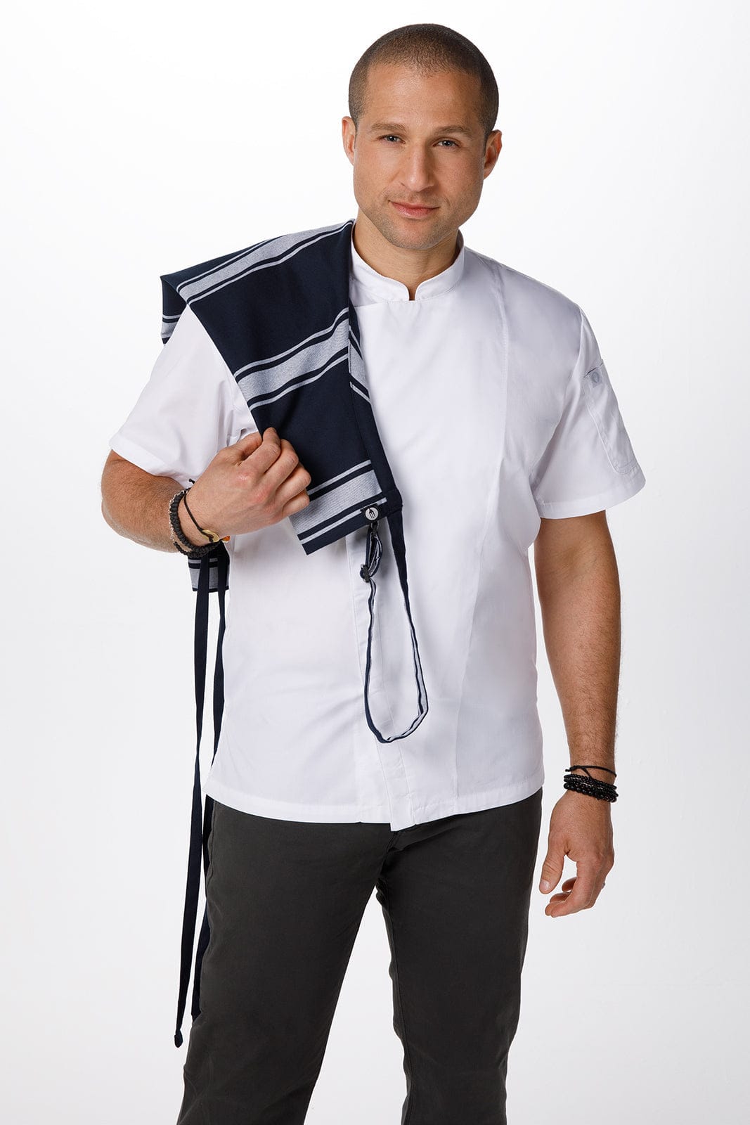 A man wears a white chef uniform and holds a navy butcher stripe bib apron with ties. The apron features a striped design.