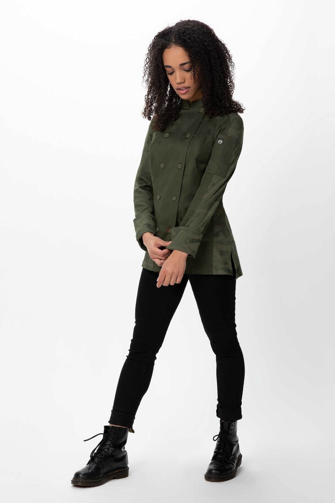 A women's chef jacket in olive green with a fitted design, featuring a logo and paired with black pants and boots.