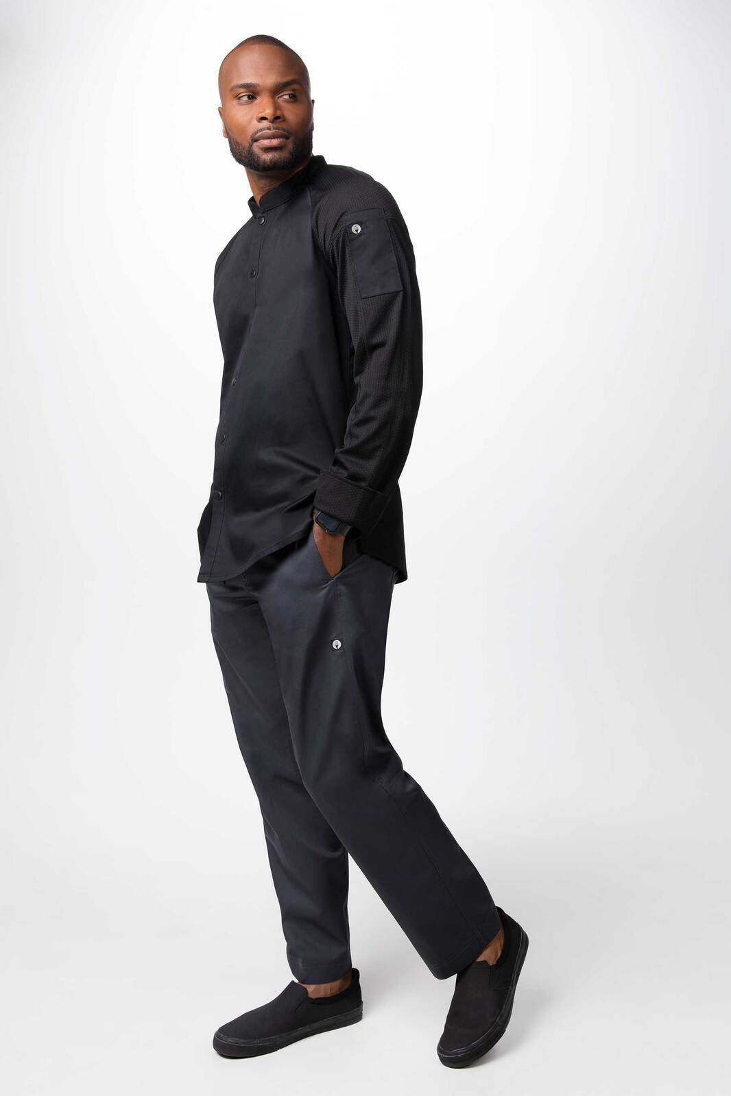 A men’s chef jacket in black, featuring a simple design and logo, worn with matching pants.
