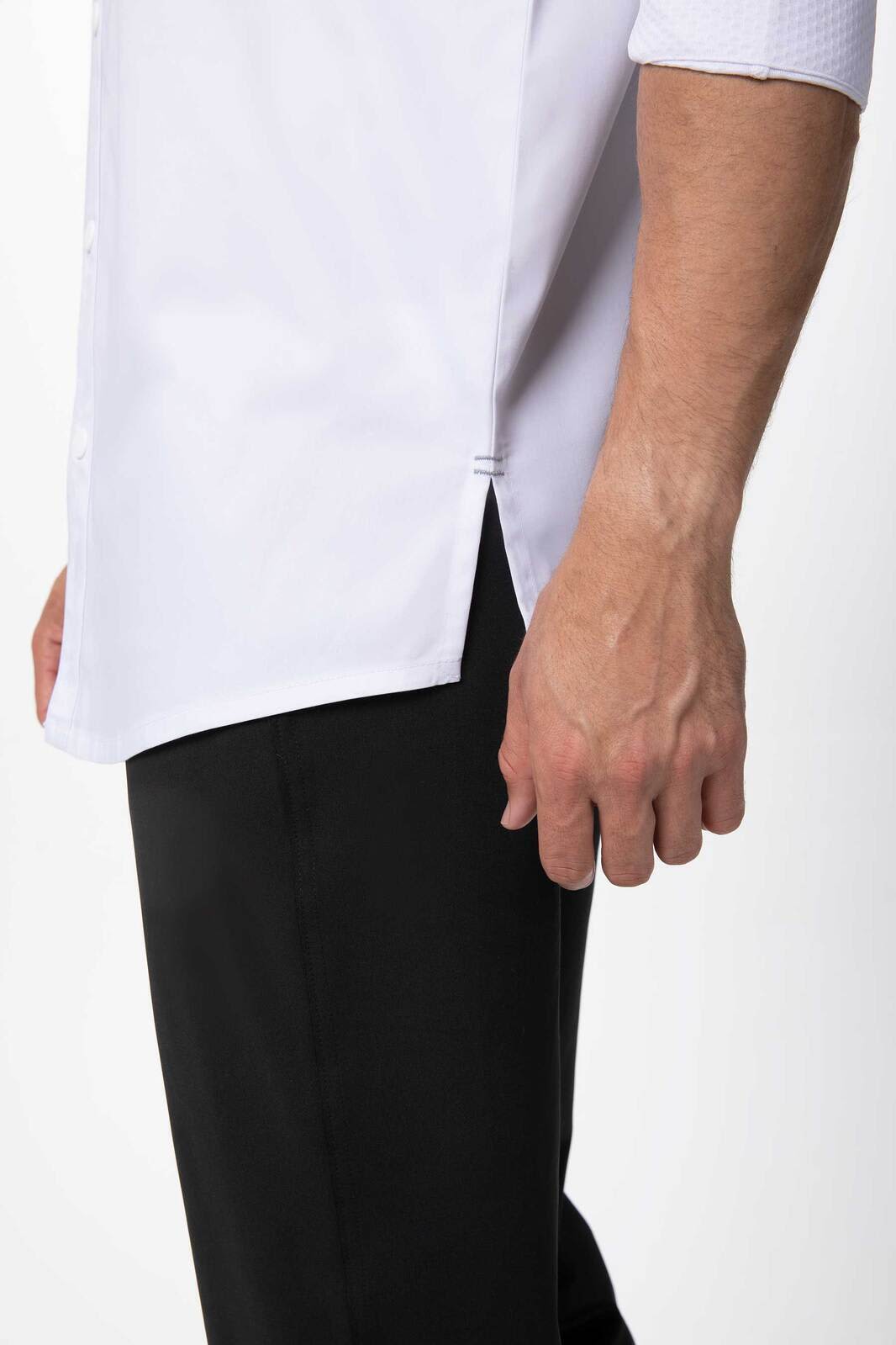 A white chef jacket with short sleeves, featuring side slits, paired with black pants. The image highlights the fabric and fit.
