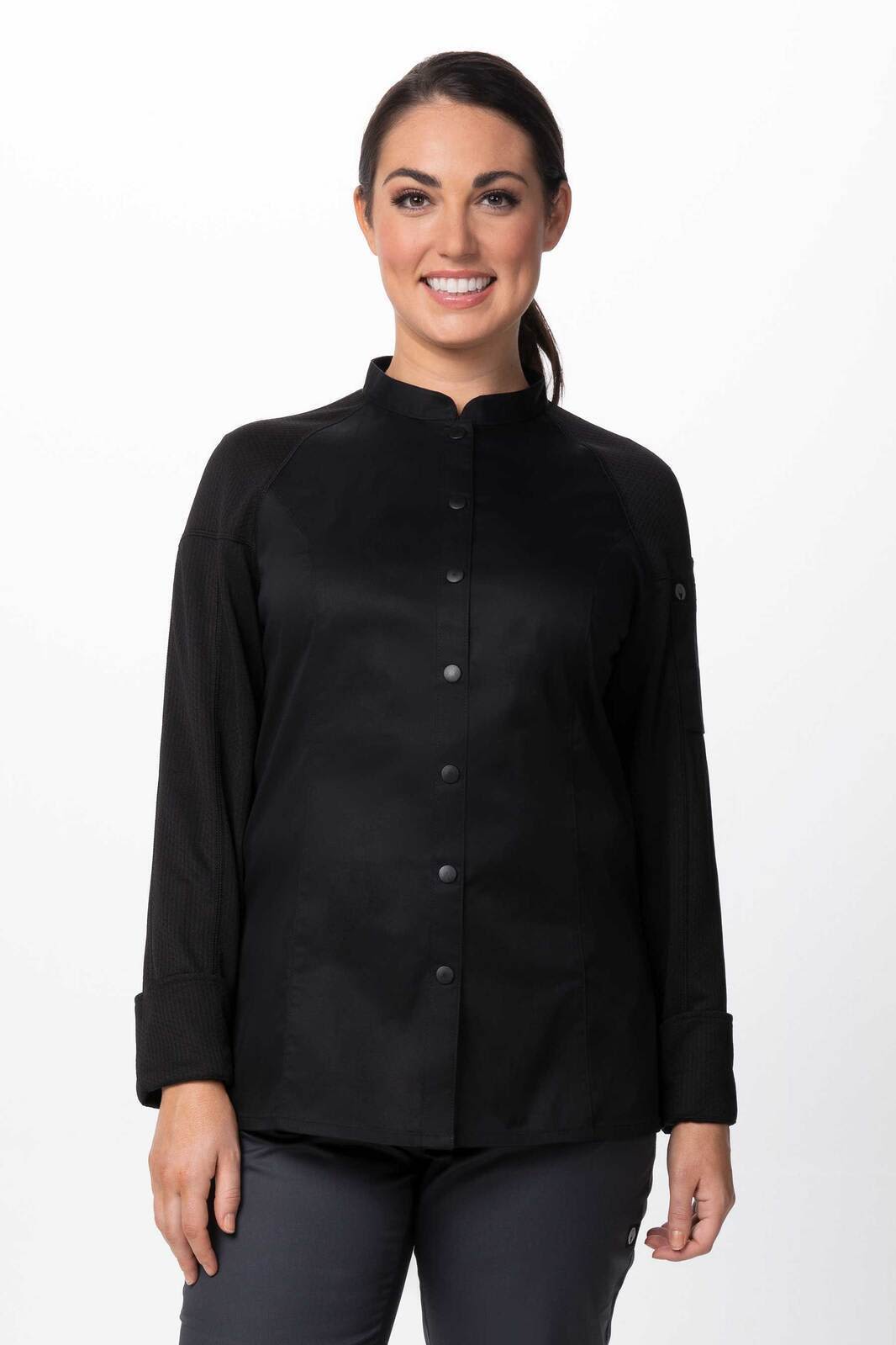 A woman wearing a black chef jacket with a mandarin collar and long sleeves, featuring a subtle logo.