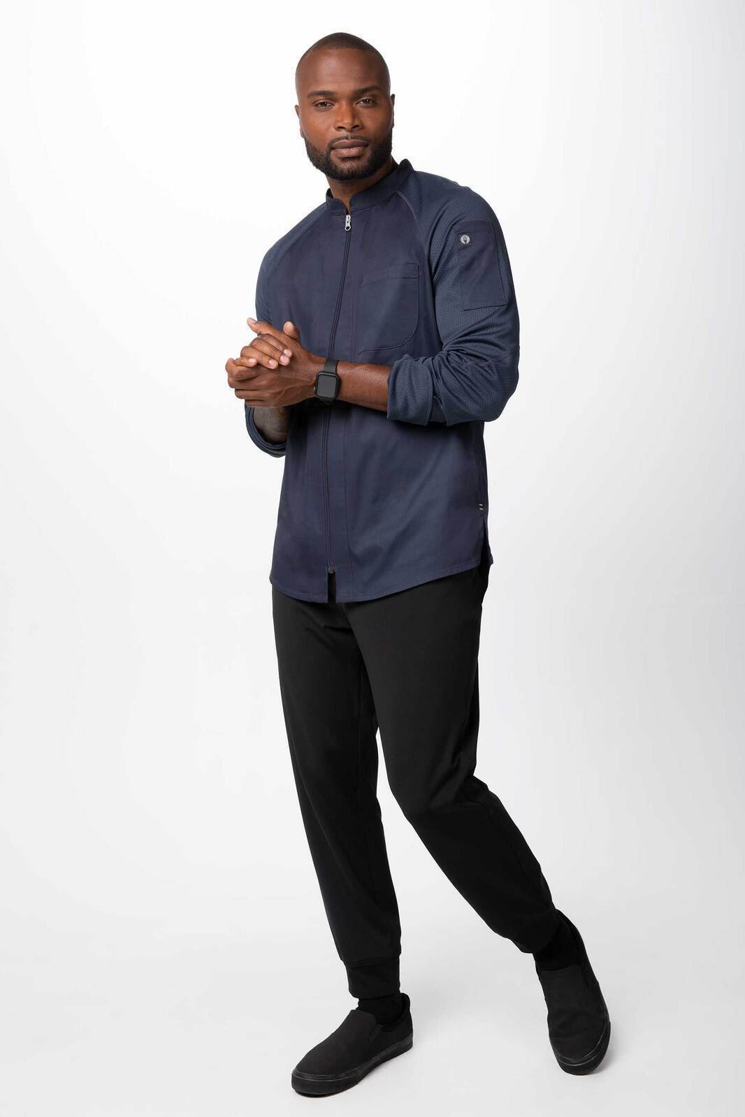 A men's chef jacket in navy blue, featuring a zipper and a logo, paired with black pants and shoes.