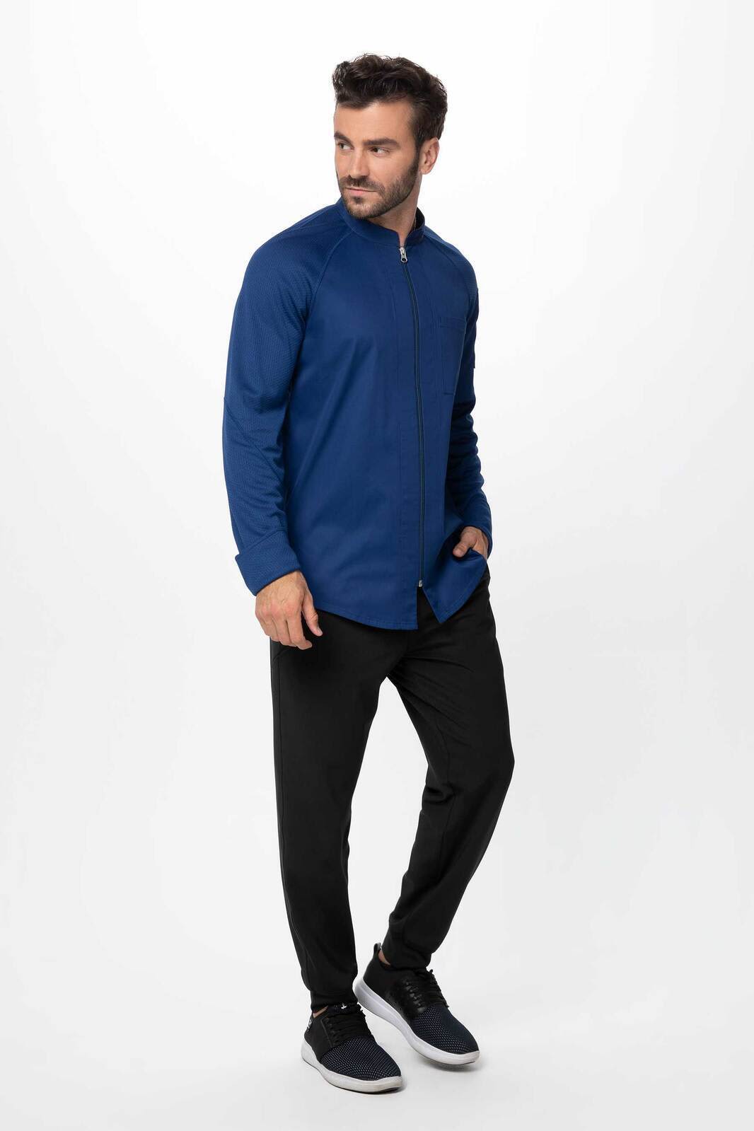 A men's chef jacket in navy blue worn with black pants, featuring a logo on the chest.