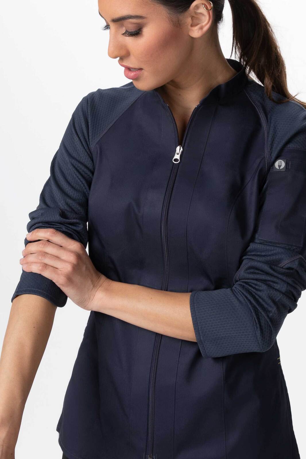 A women's chef jacket in navy blue with contrasting sleeves and a zipped front, featuring a logo on the sleeve.