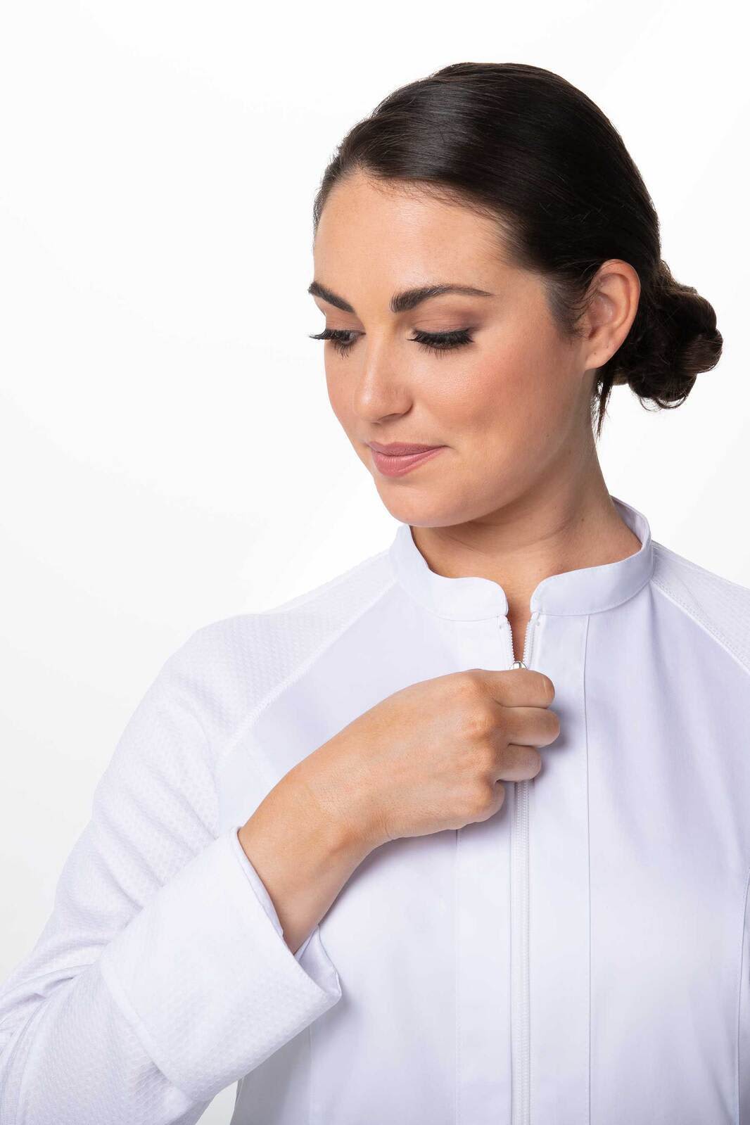 A white chef's jacket featuring a zip closure, with a model adjusting the collar. The design is sleek and modern.