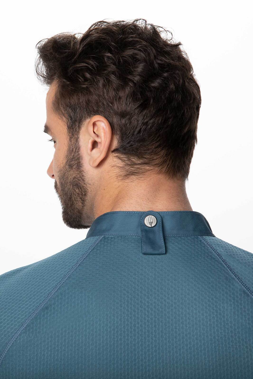A men's chef jacket in dark teal featuring a textured fabric and a button detail at the collar.
