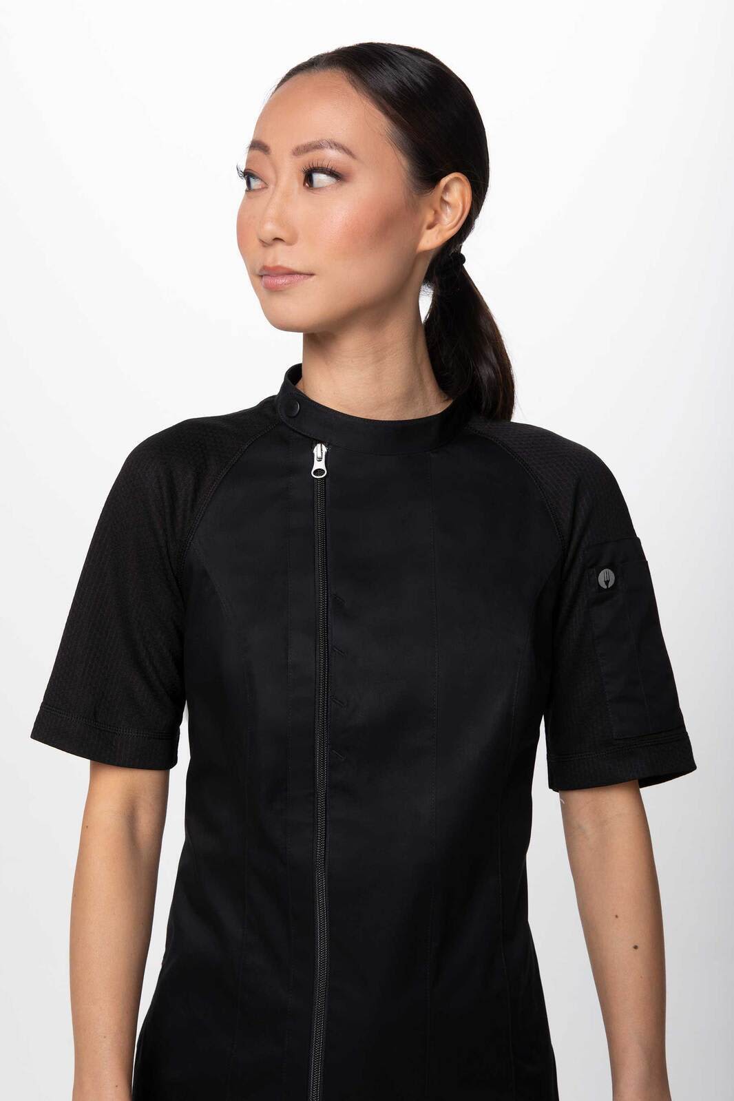 A black women's chef jacket featuring short sleeves and a zip front, with a logo on the sleeve.