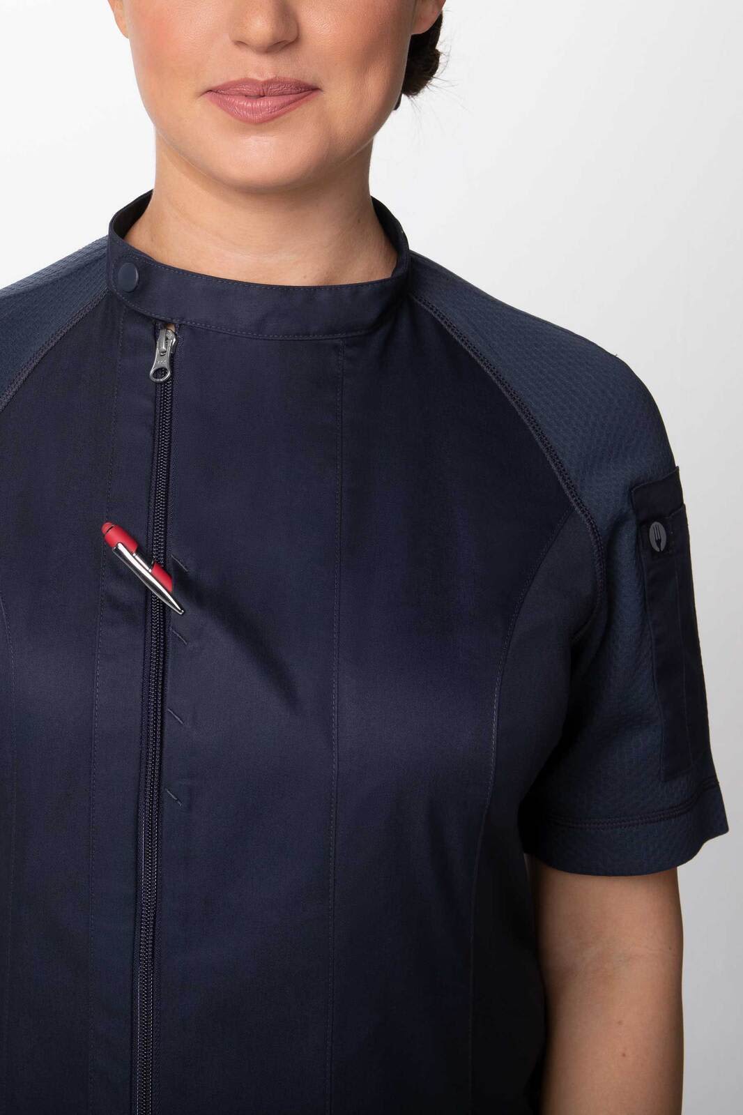 A navy women's chef jacket featuring a zipped front and a pocket, worn by a model.