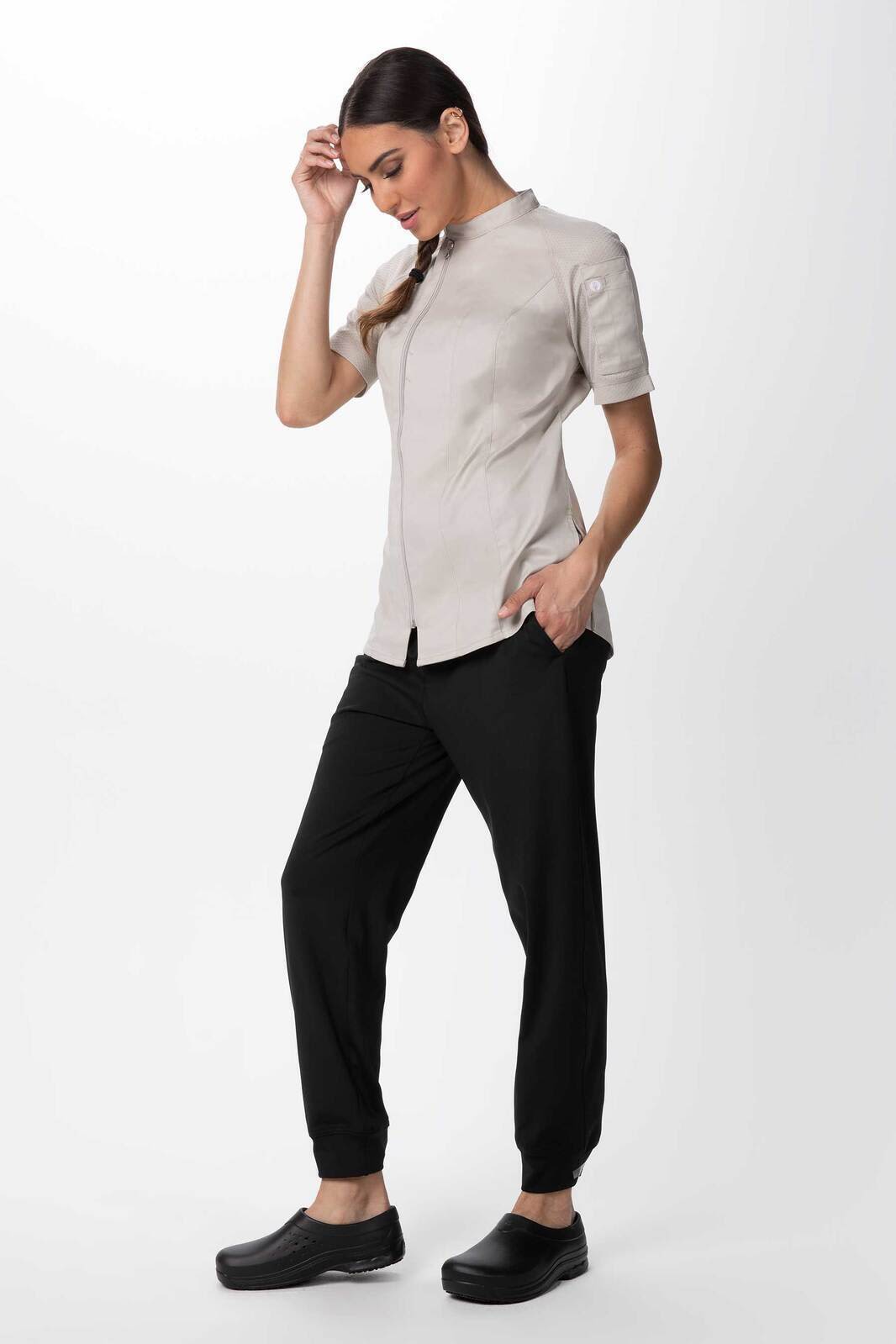 A light grey women's chef jacket with short sleeves, paired with black pants and shoes, featuring a logo.