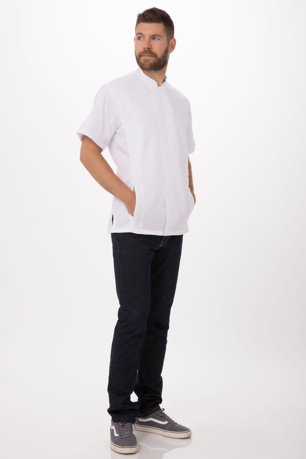 A men's chef jacket in white with short sleeves, paired with dark jeans and grey shoes, featuring a logo.