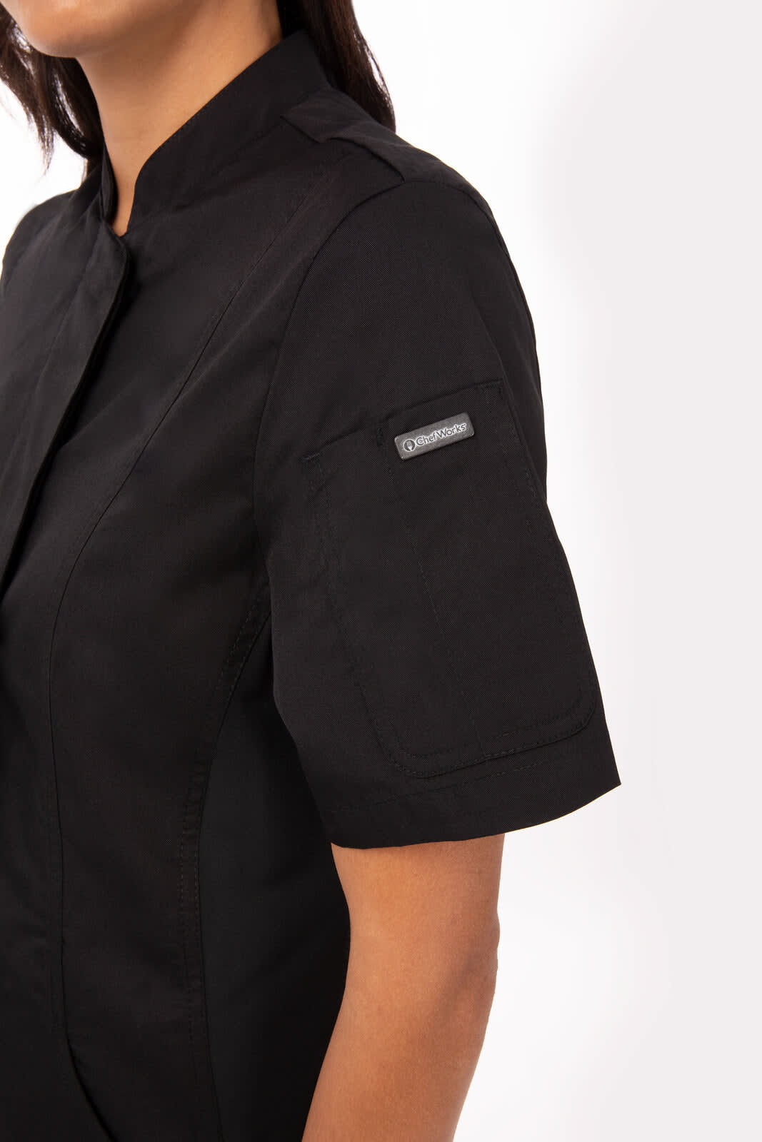 A black women's chef jacket with short sleeves, featuring a sleek design and an attached logo on the sleeve.