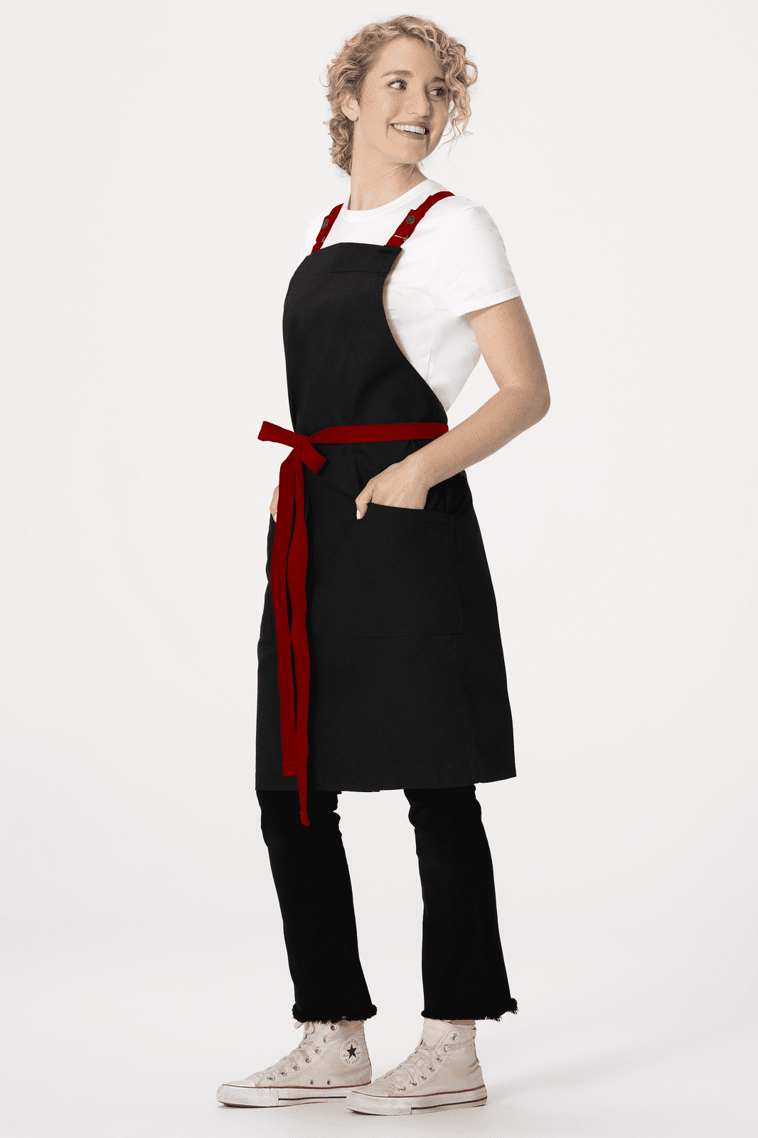 A black apron with a red belt and pockets, worn over a white t-shirt and black trousers. It features a logo.