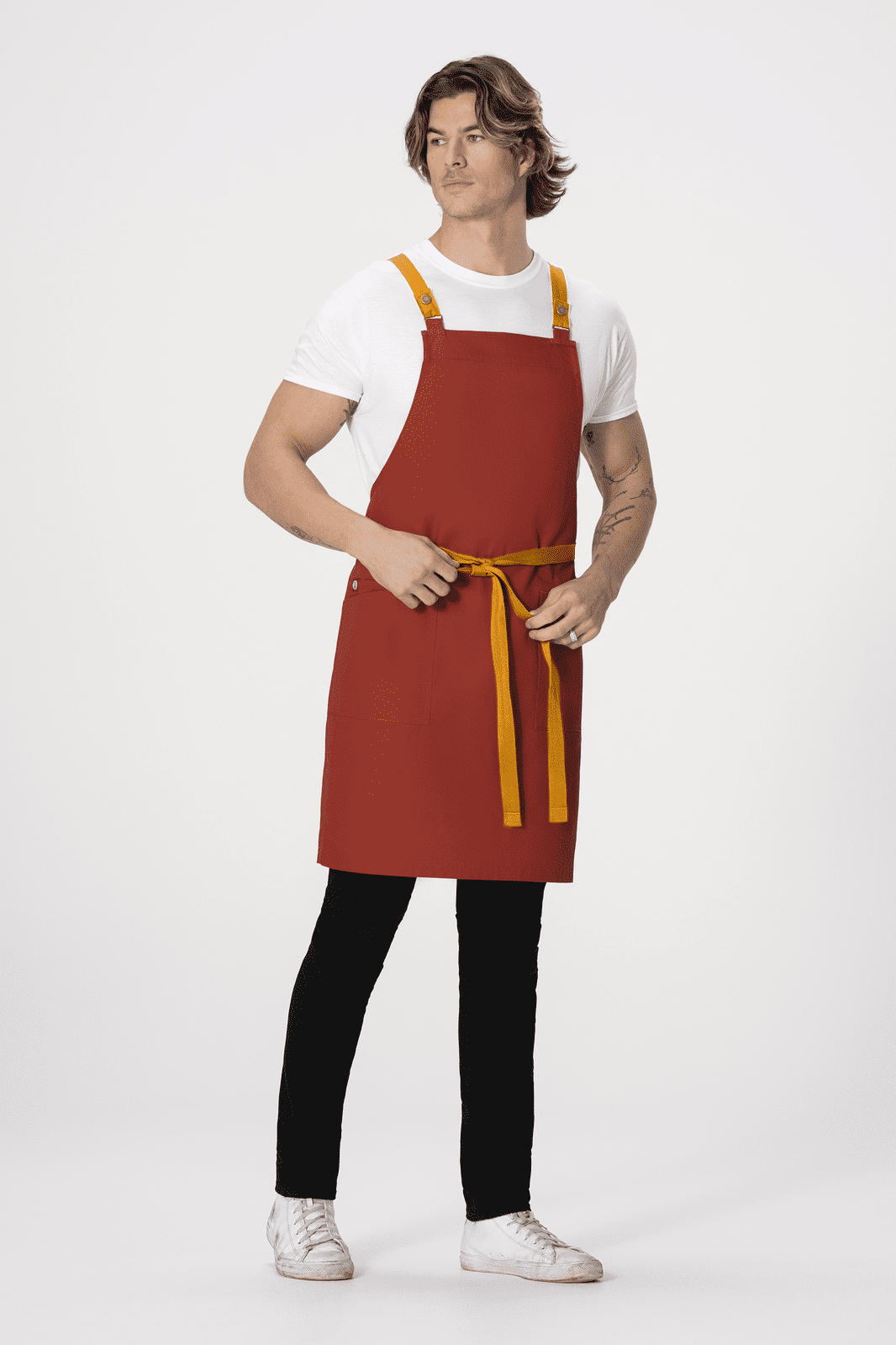A red cross back apron is worn by a model, featuring yellow straps and a tie, against a white background.