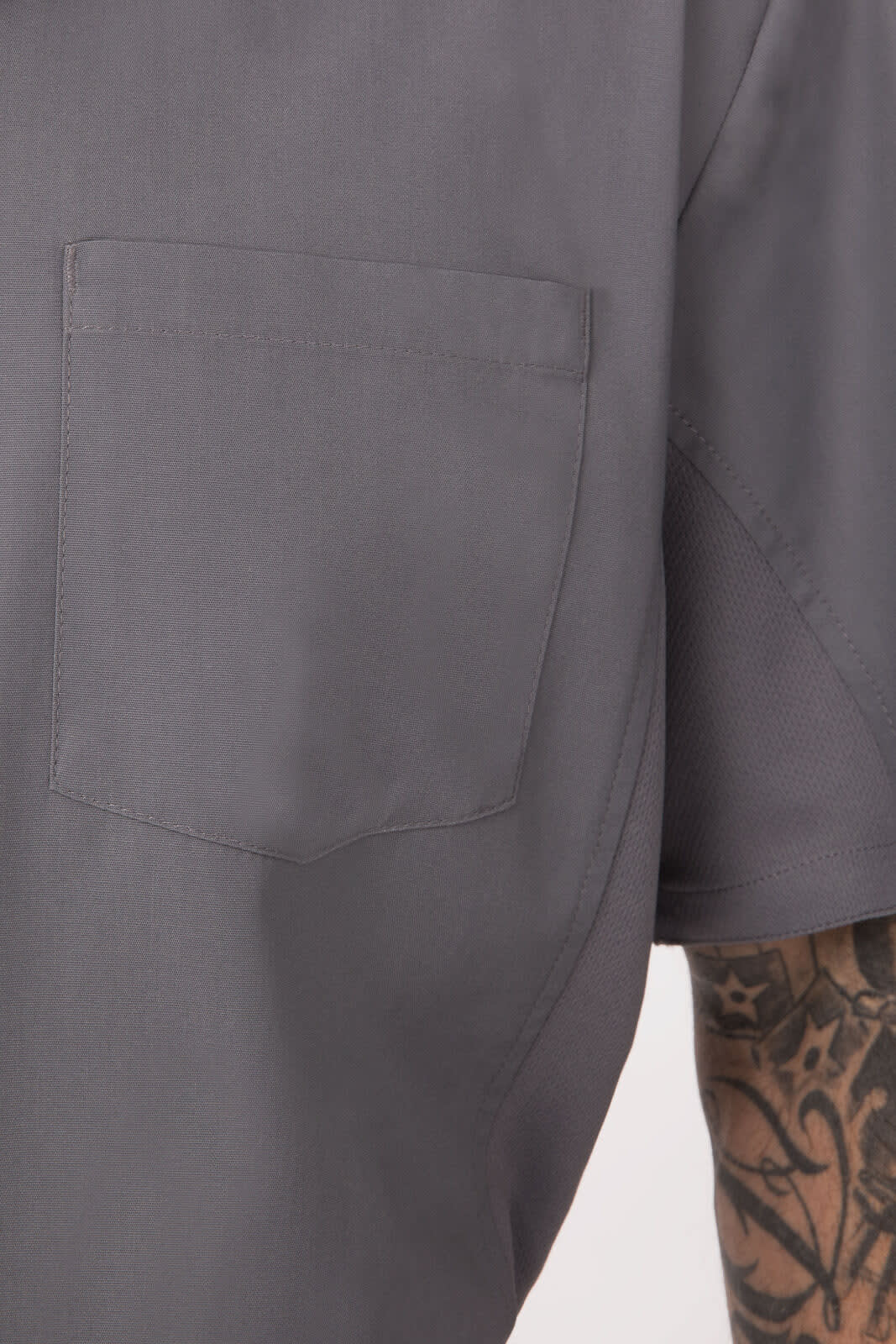 A grey men's shirt featuring a patch pocket and short sleeves, with a visible logo on the fabric.