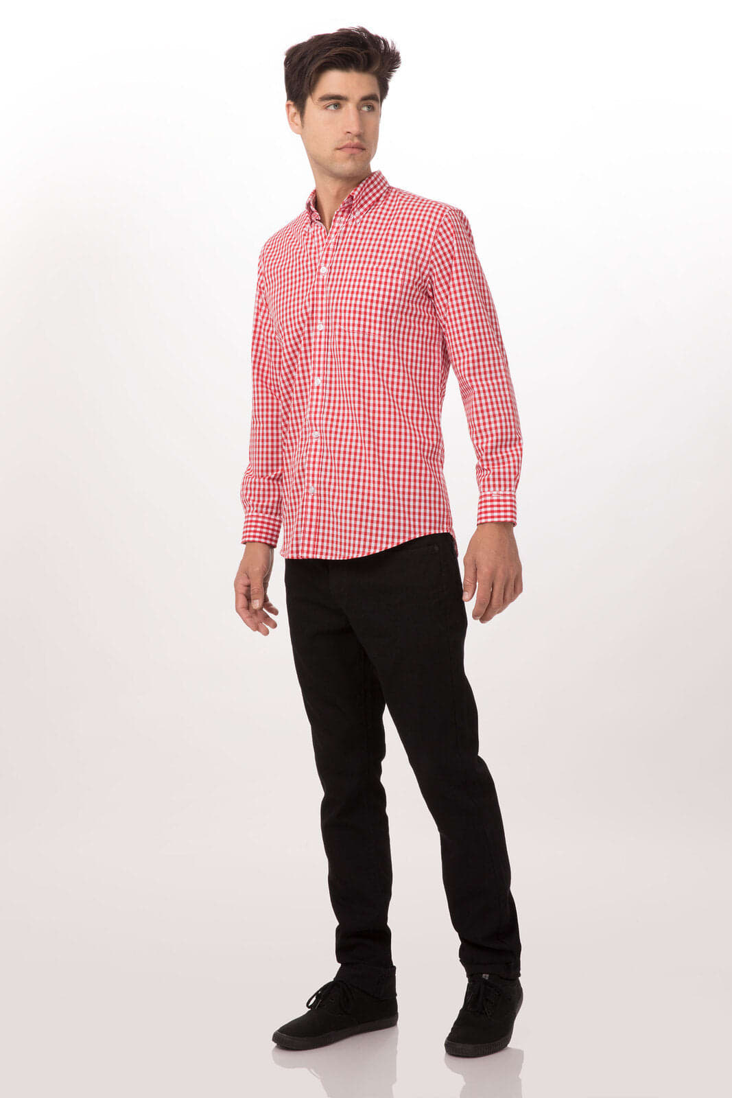 A man in a red and white checkered button-up shirt stands next to a plain background, wearing black trousers.