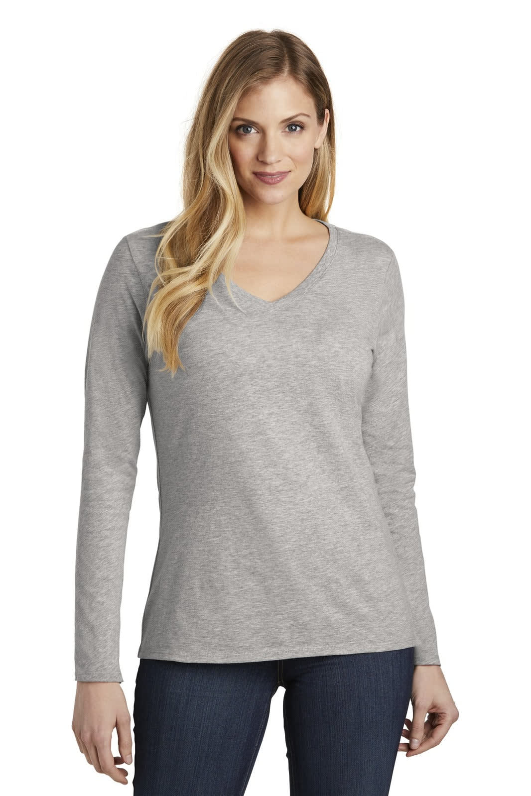 A woman models a grey long sleeve v-neck t-shirt. The shirt has a logo on it and is styled with jeans.