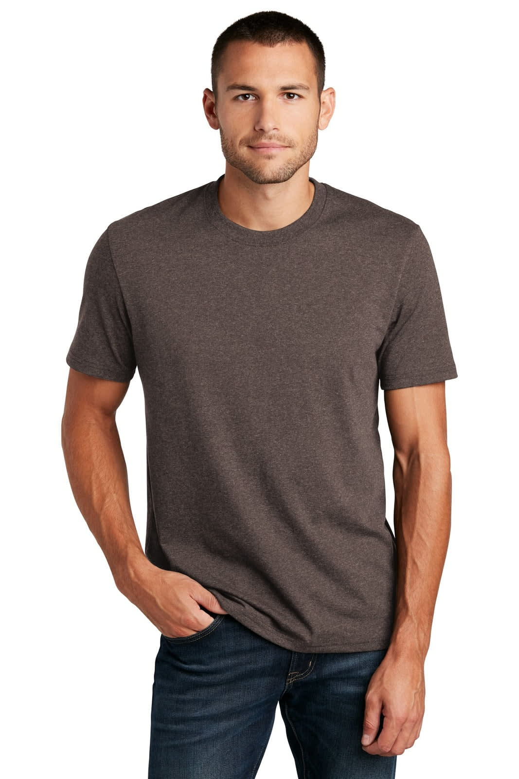 A man stands wearing a brown t-shirt, paired with dark jeans. The shirt features a logo on it.