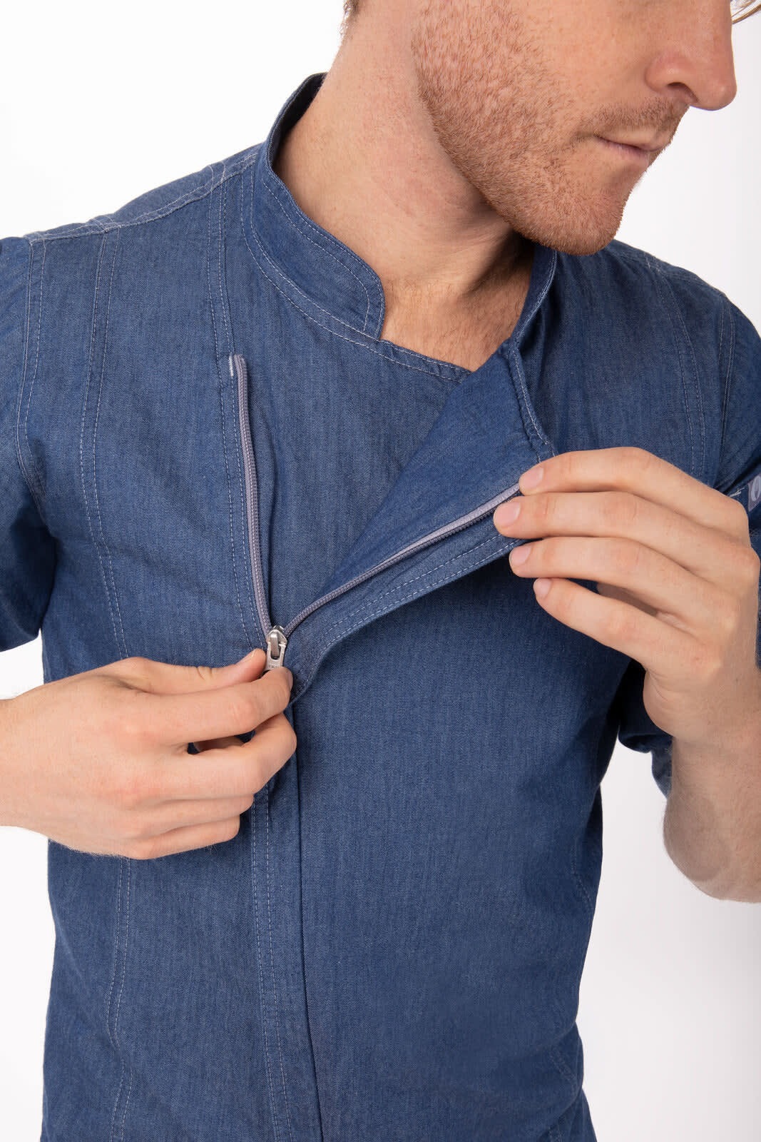 A denim chef jacket in blue, featuring a zippered front and a stand-up collar, with a logo on the chest.