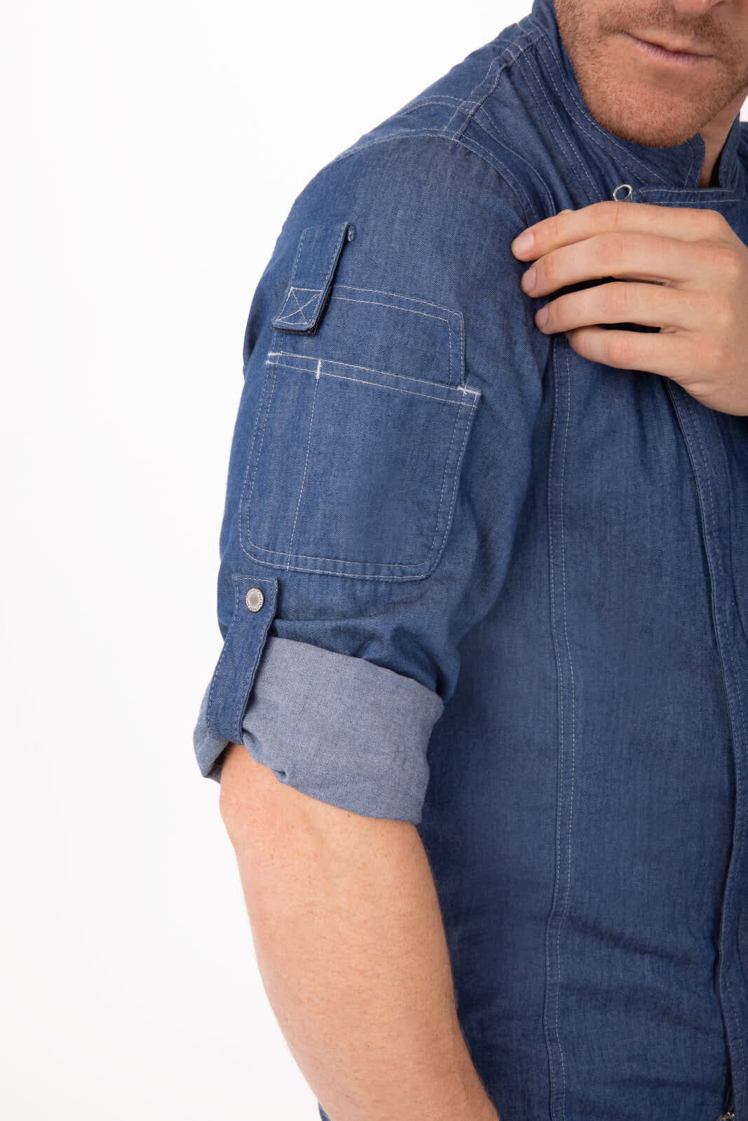 A denim chef jacket with rolled sleeves and a patch pocket on the arm, featuring a small logo.
