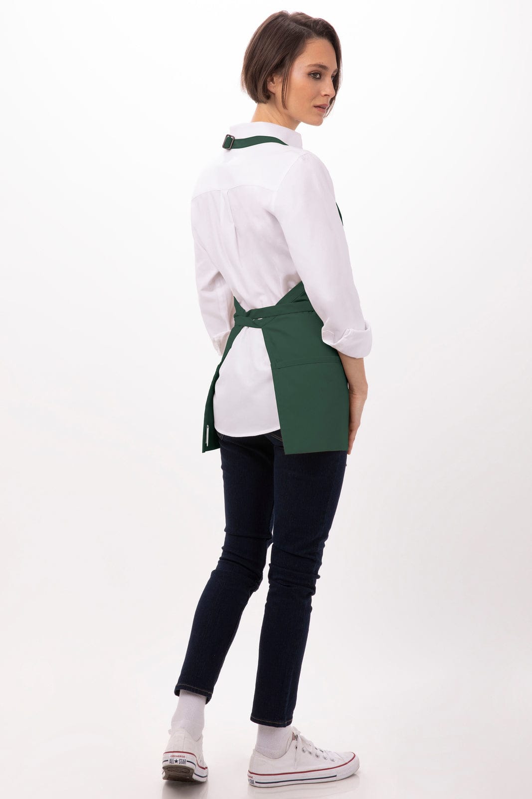 A green three-pocket apron worn over a white shirt, displayed from the back, paired with dark jeans and white shoes.