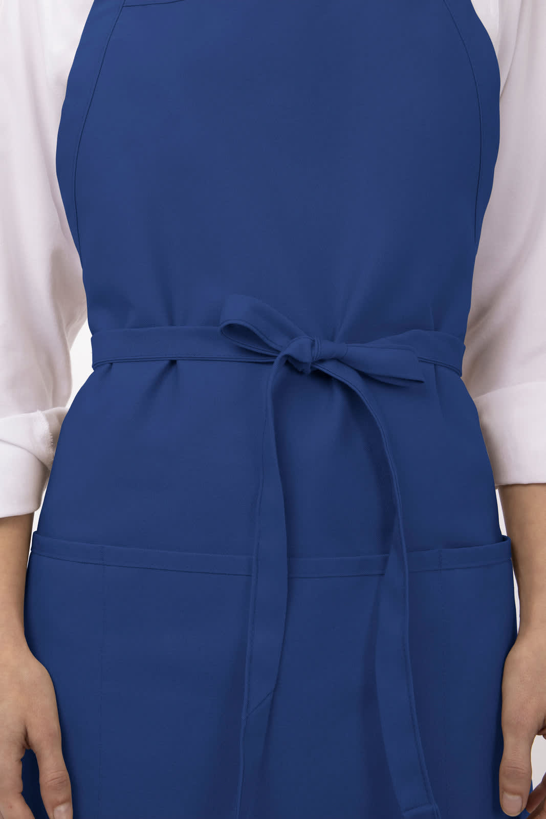 A blue three-pocket apron featuring a waist tie, worn by a person with hands in pockets. The design includes a logo.