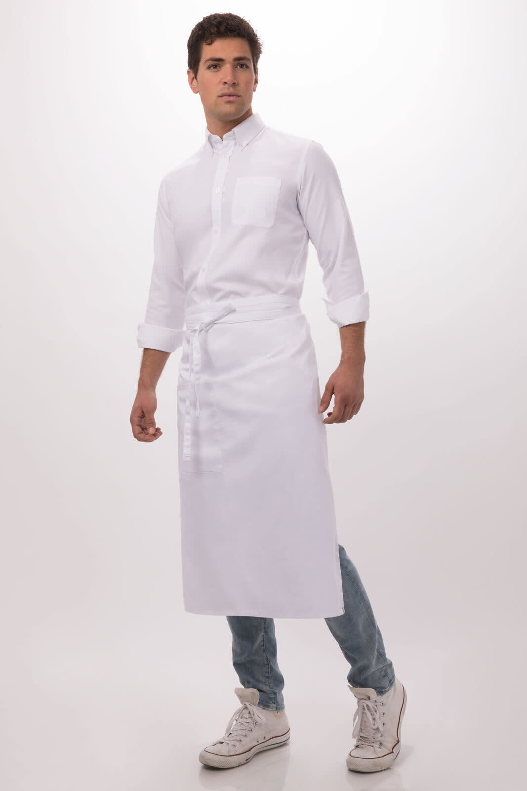 A man wearing a white bistro apron over a long-sleeve shirt and jeans, standing against a light background.