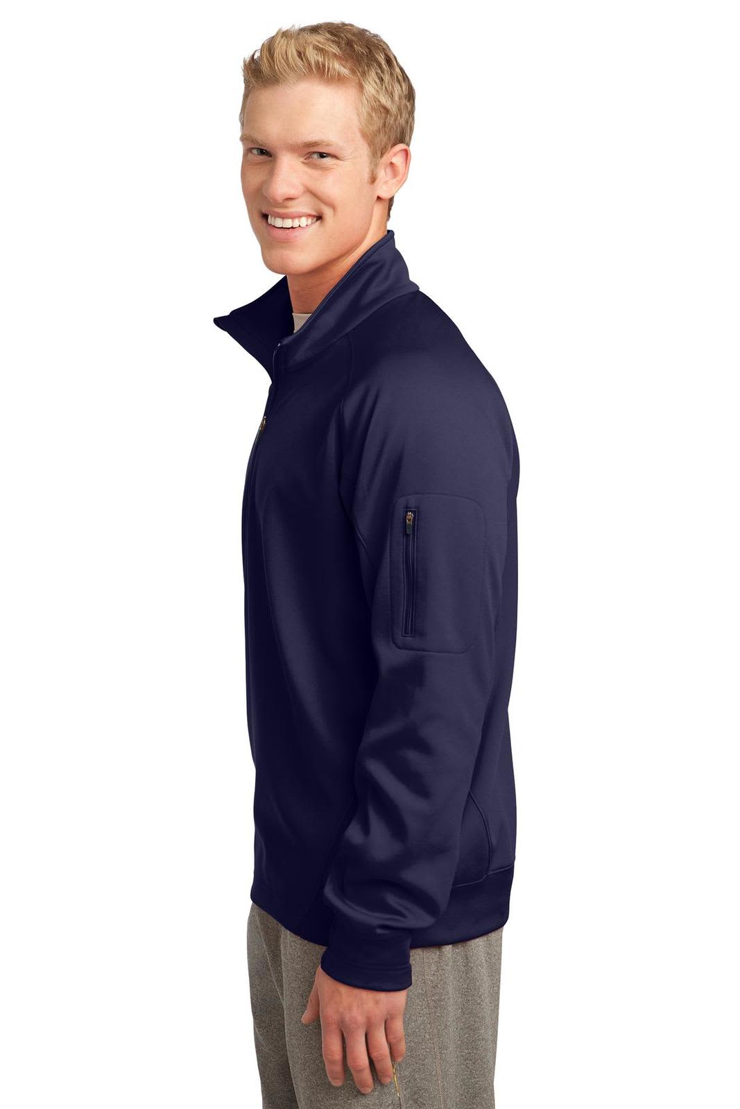 A navy blue Sport-Tek Tech Fleece 1/4-Zip Pullover with a zip pocket on the sleeve, modelled by a smiling person.