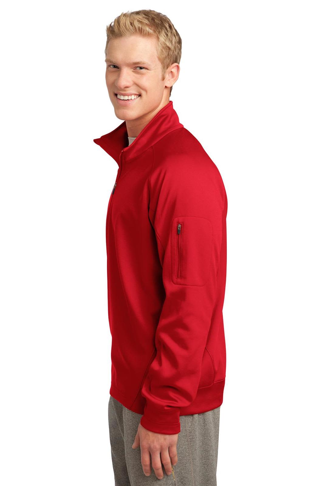 A red Sport-Tek Tech Fleece 1/4-Zip Pullover is worn by a smiling man, featuring a zippered pocket on the sleeve.